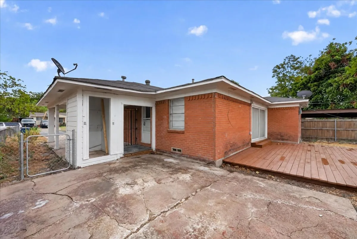 Brick exterior with a wood deck and an attached covered structure