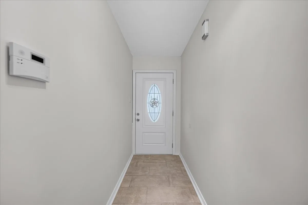 Entryway featuring light-toned tile flooring, light neutral wall paint, and a white door with decorative glass inlay