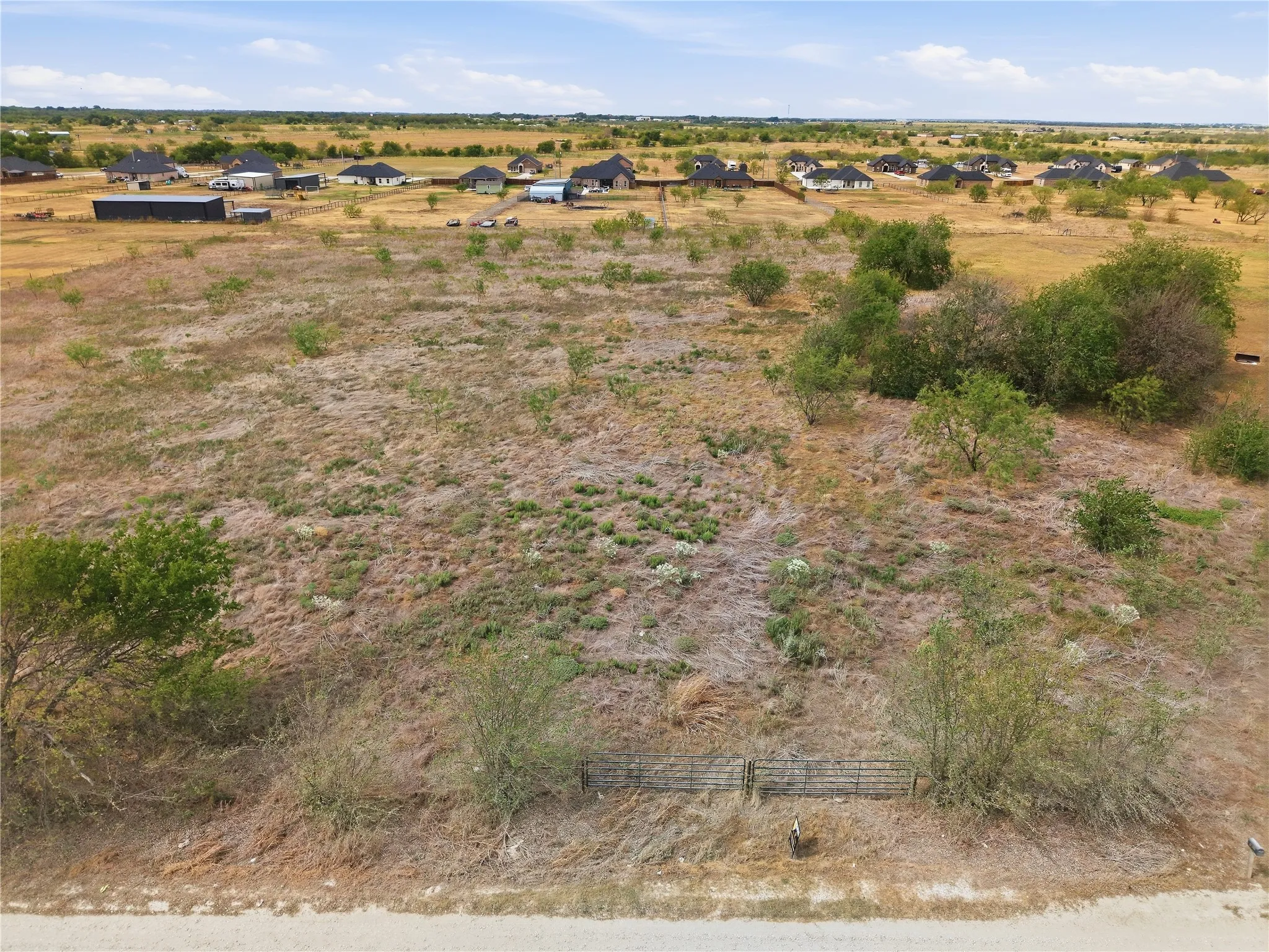 Expansive lot featuring varied natural vegetation and distant residential structures
