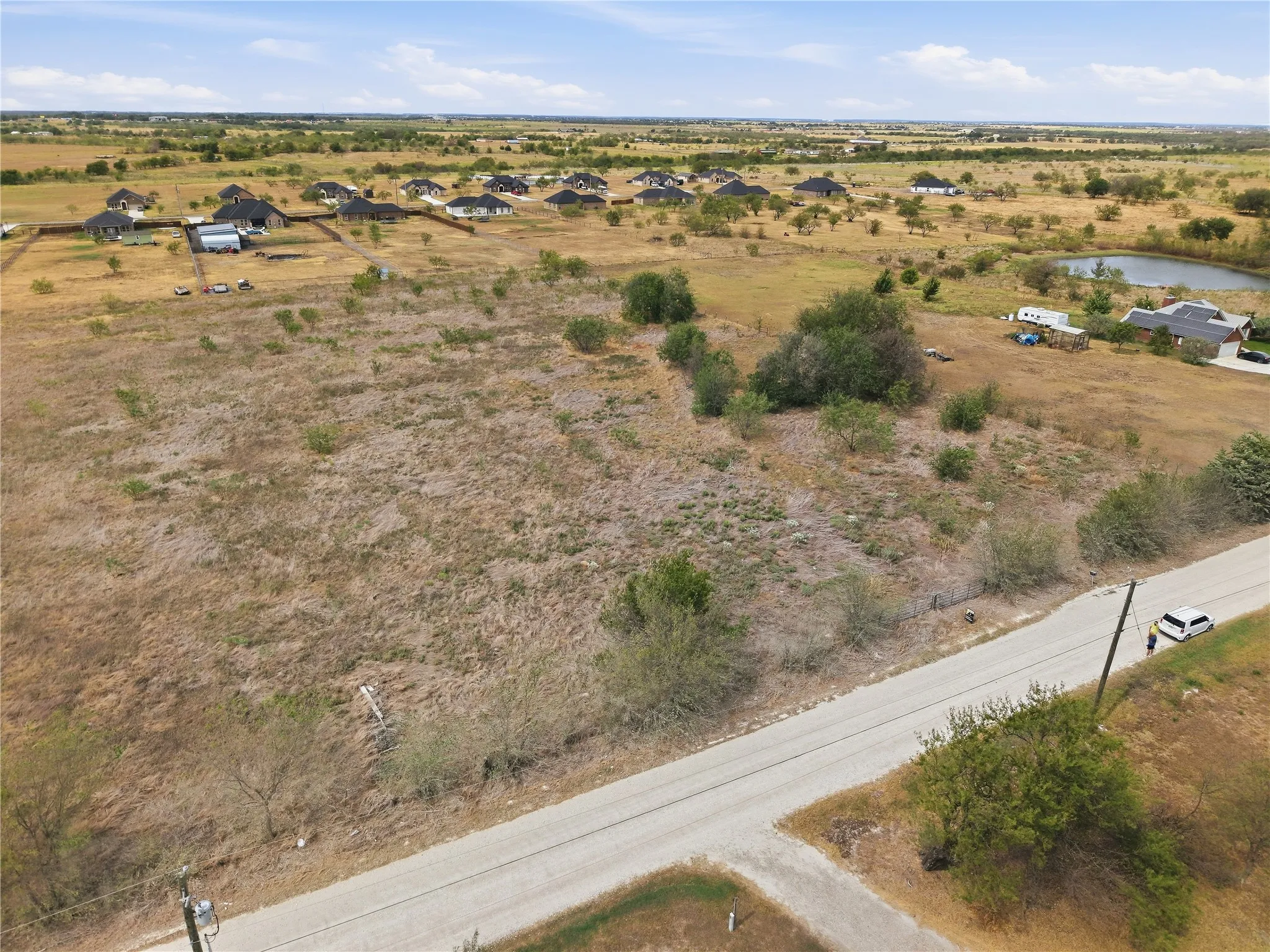 Expansive undeveloped land featuring natural foliage and a visible road frontage