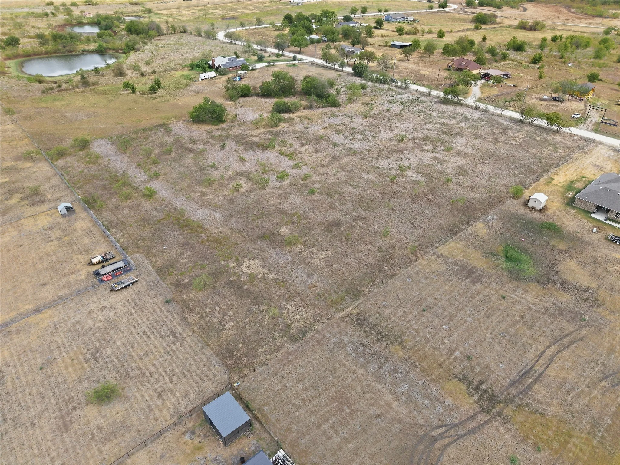 Expansive undeveloped land with a partial fence line and scattered mature trees