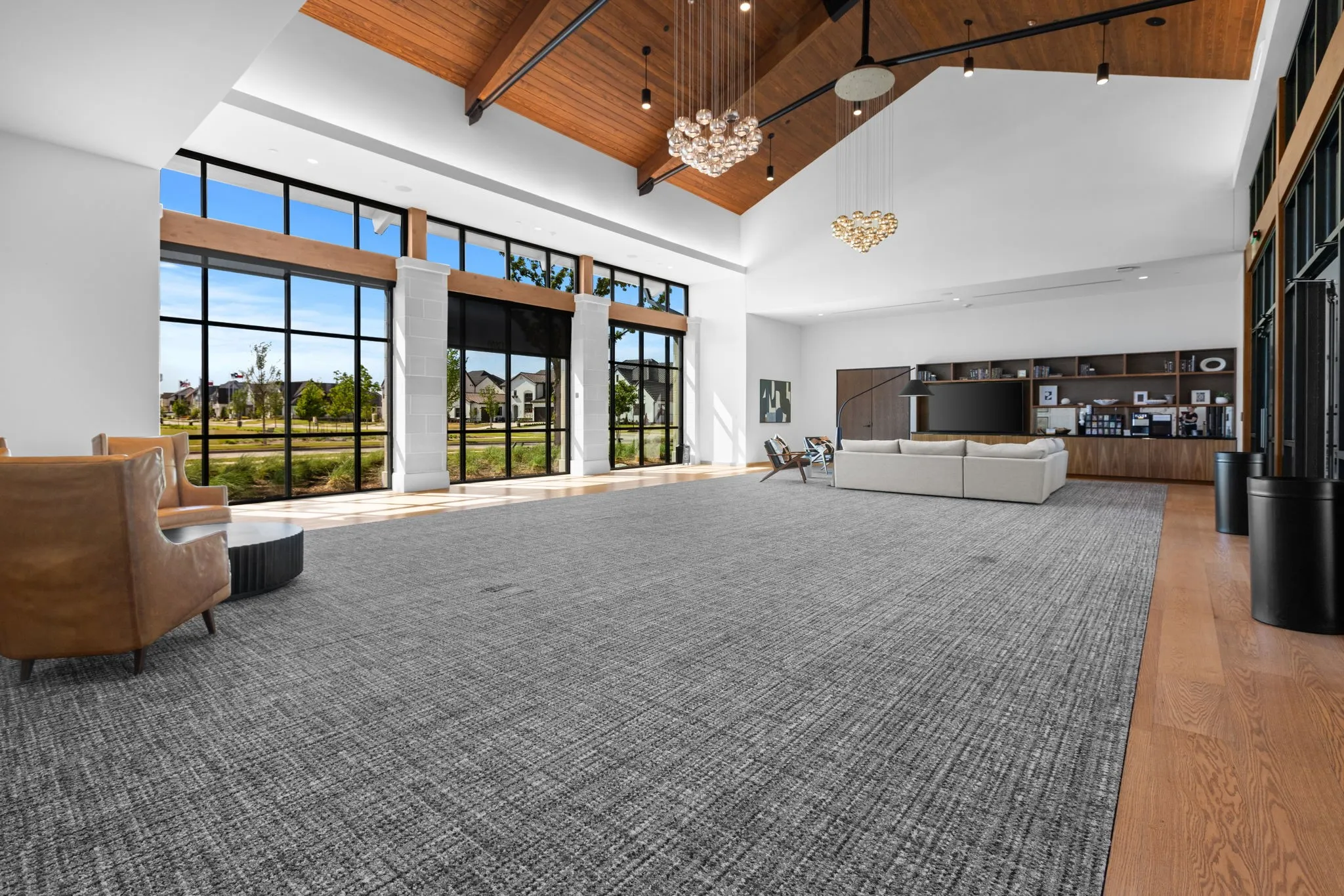 Community Expansive open-concept living space featuring soaring wood-beam ceilings, skylights, and abundant natural light from multi-panel glass doors and transom windows