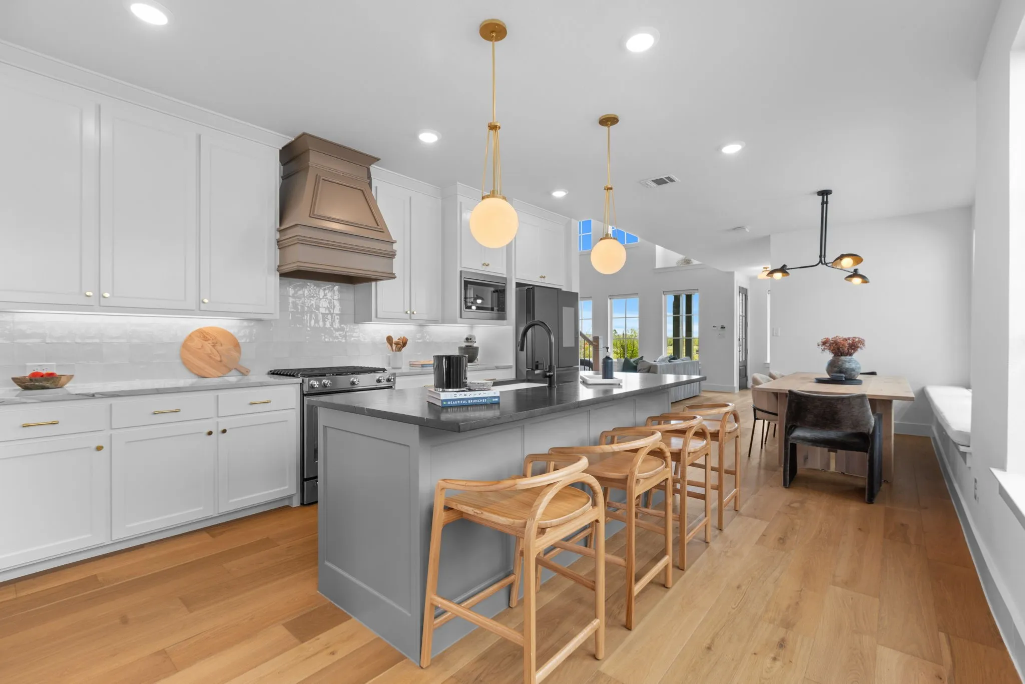 Modern kitchen featuring white cabinetry, a gray island with seating, a built-in range hood, and wood-finish flooring