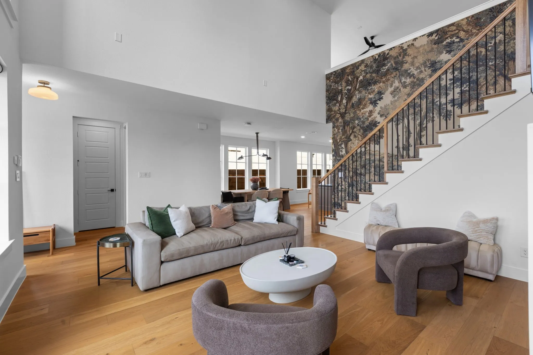 Vaulted ceiling, wood-finish flooring, staircase with natural wood handrail, black metal balusters, and a decorative wall feature