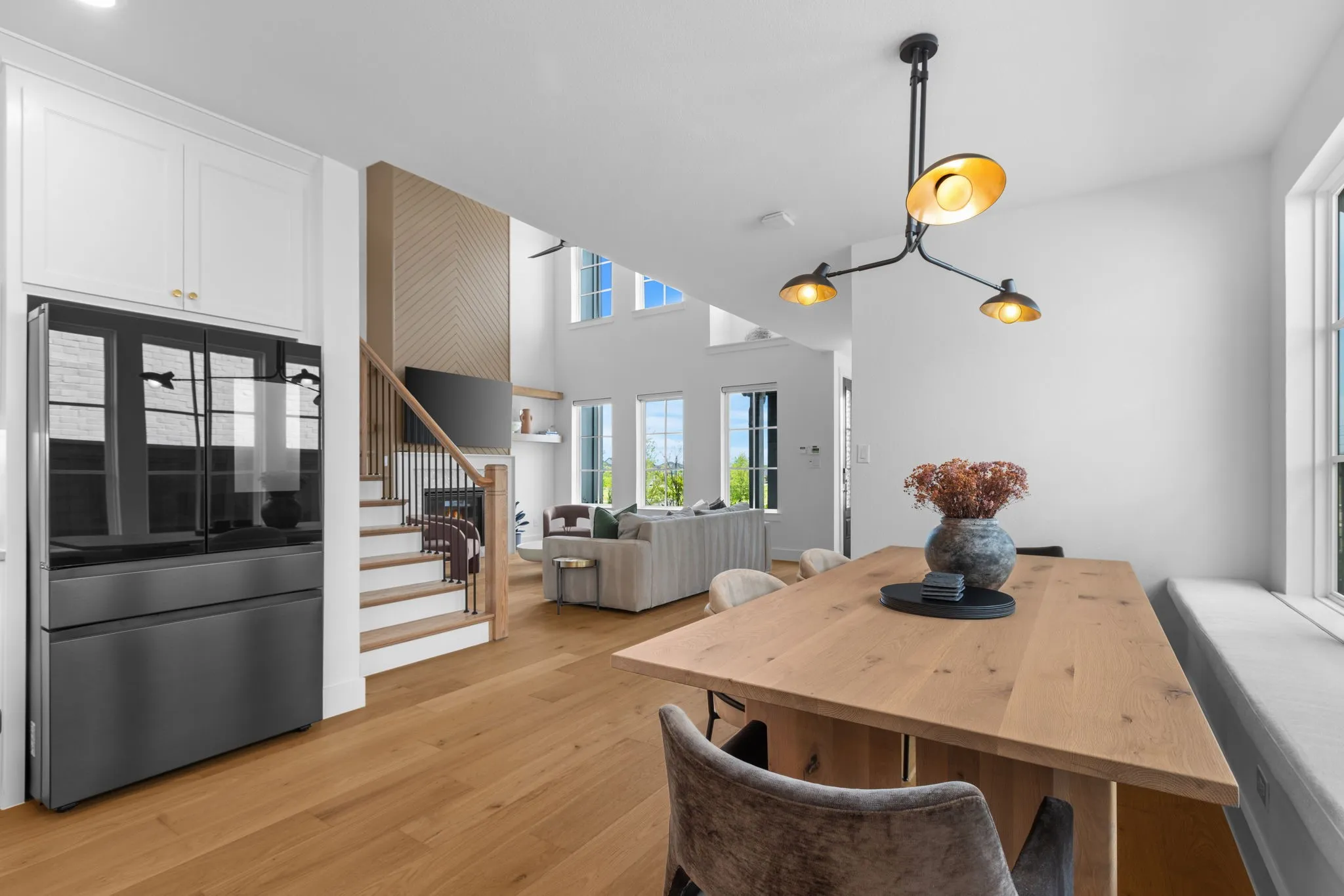 Open-concept living area featuring wood-finish flooring, white cabinetry, a built-in window bench, and a modern chandelier