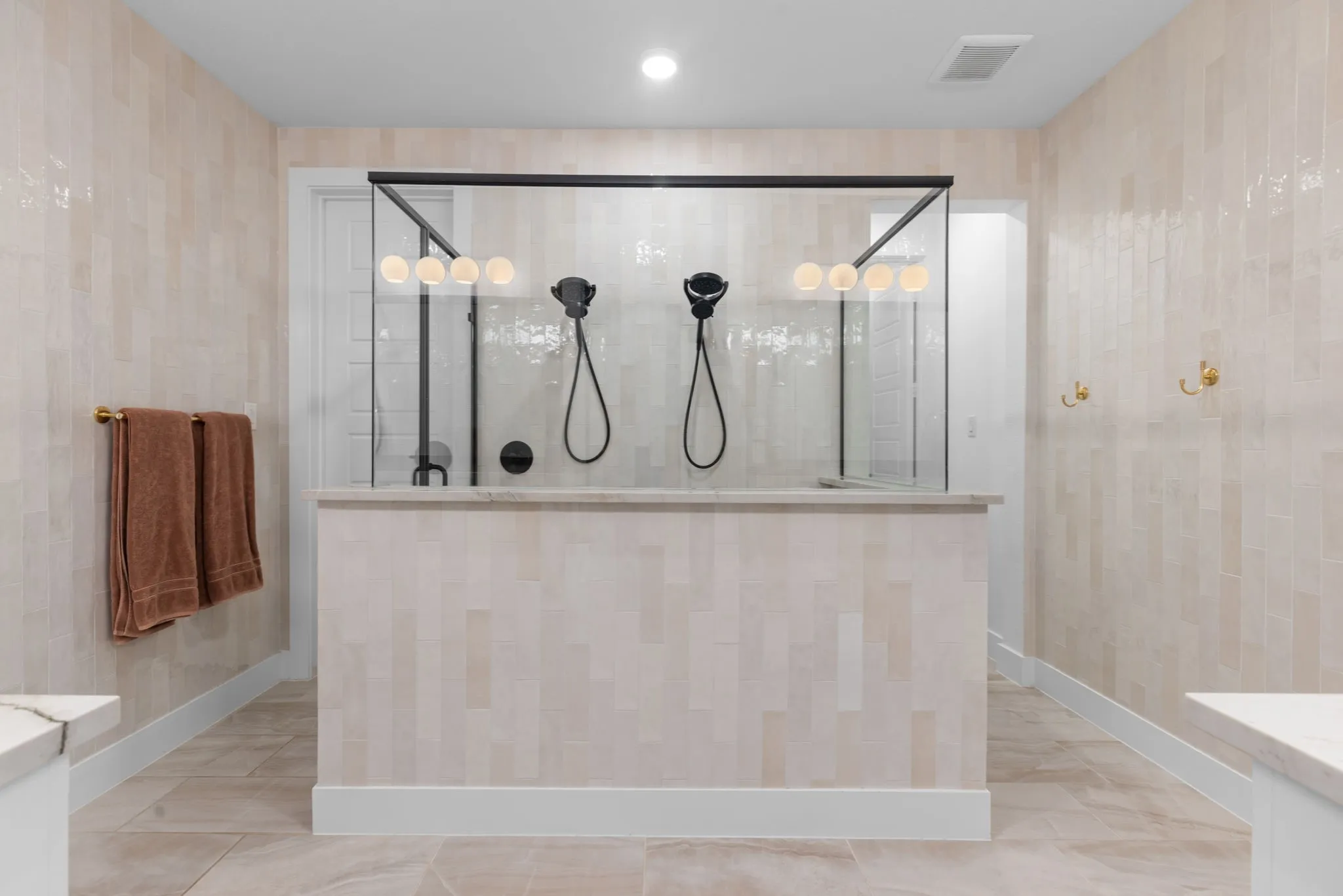 Spacious shower enclosure with glass panels, dual black shower systems, and integrated lighting
