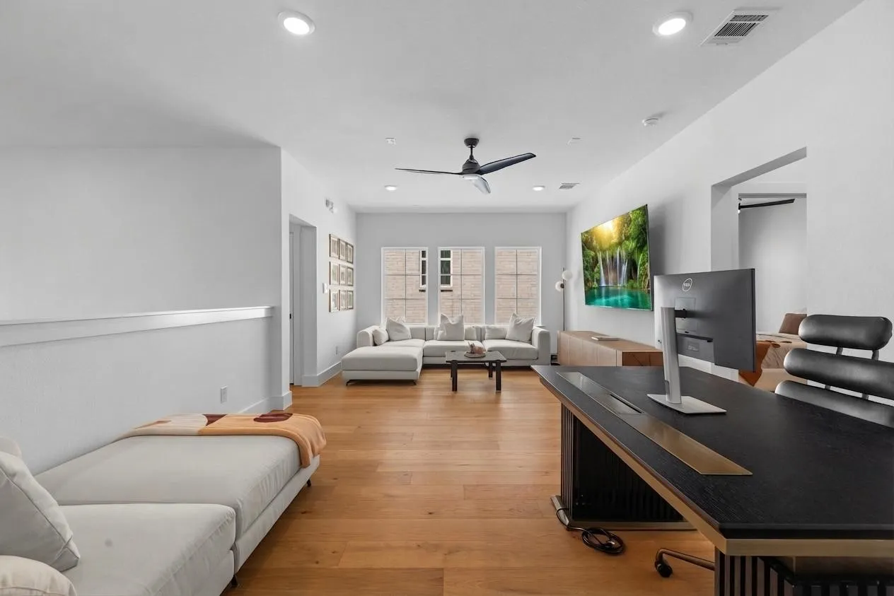 Hardwood-finish flooring throughout, featuring recessed lighting, a ceiling fan, and large windows with transom details