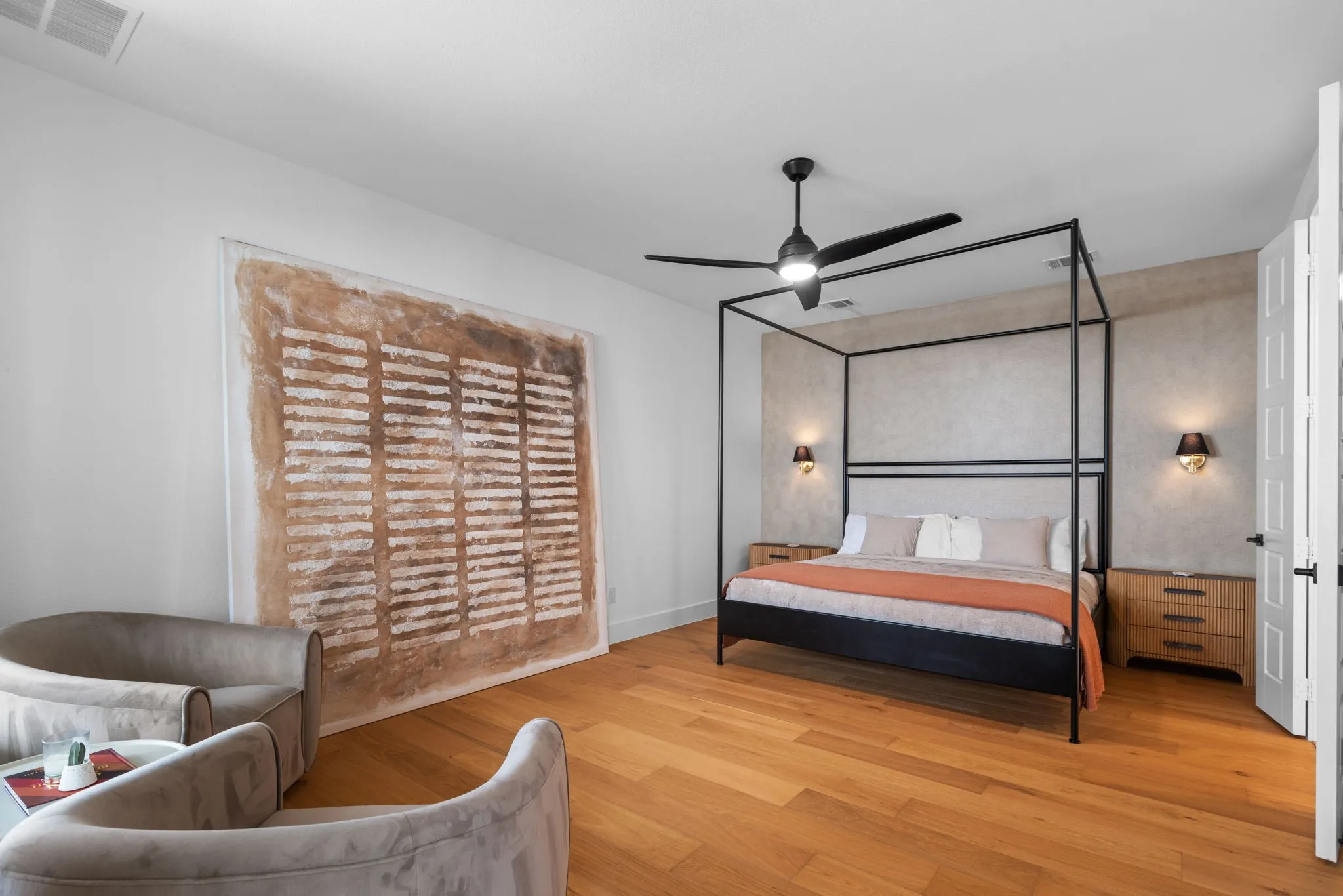 Wood-finish flooring, ceiling fan, textured accent wall, and built-in wall sconces