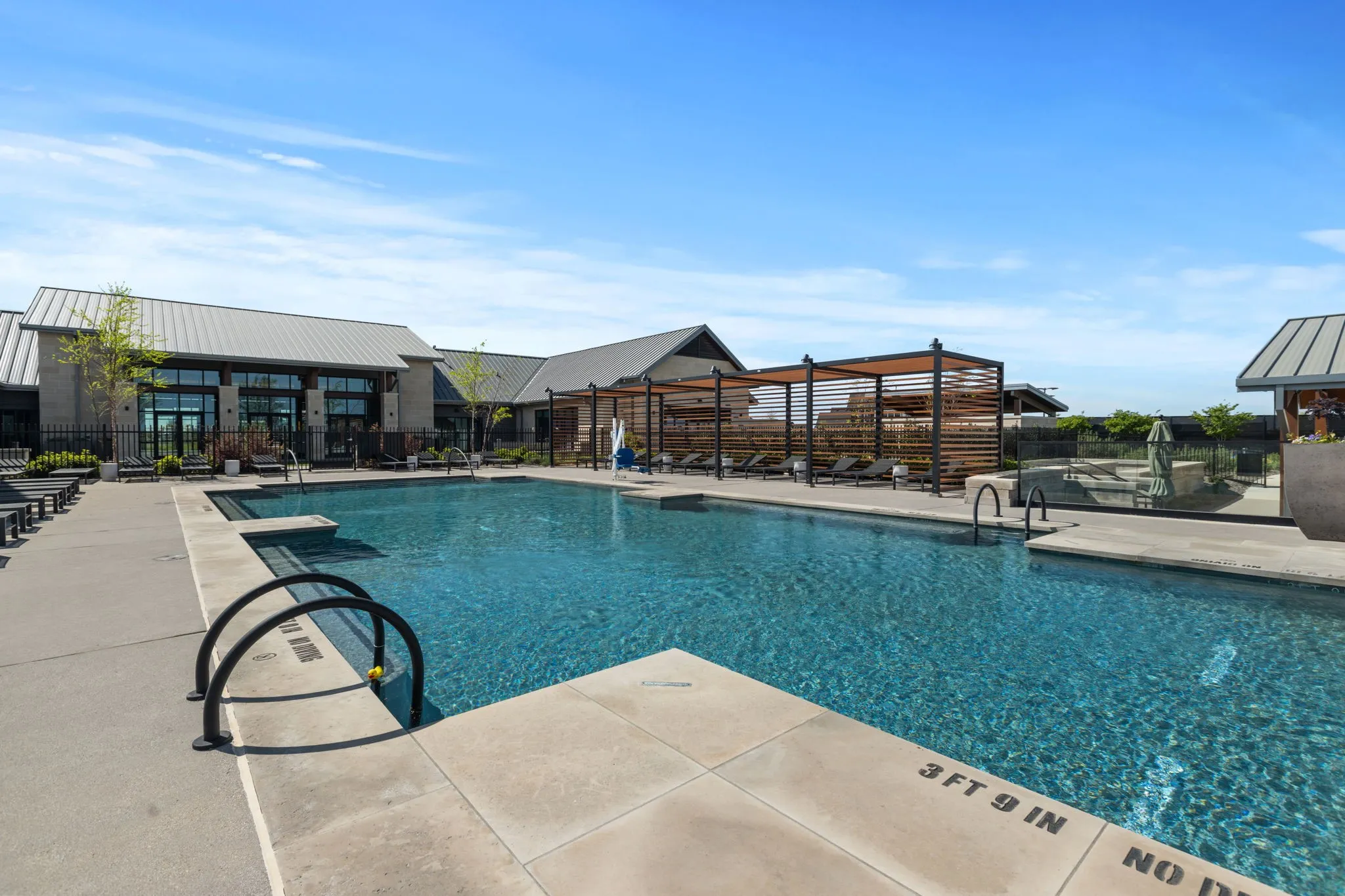 Expansive outdoor pool with integrated steps and black metal handrails