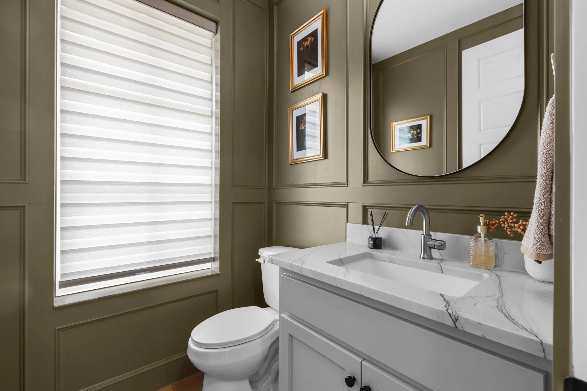 Wainscoting paneling, a single-hole faucet, and a round mirror