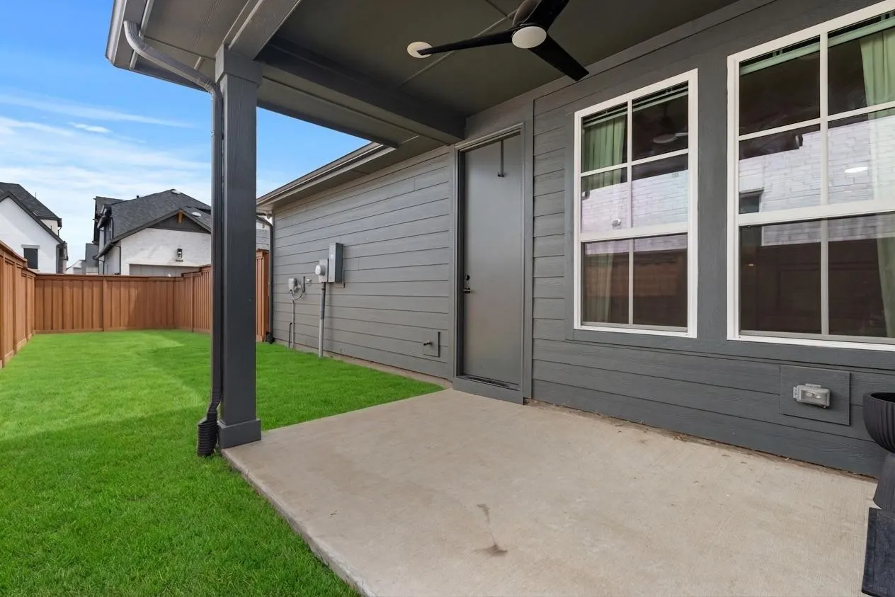 Private fenced backyard featuring a concrete patio, verdant lawn, and horizontal plank fencing