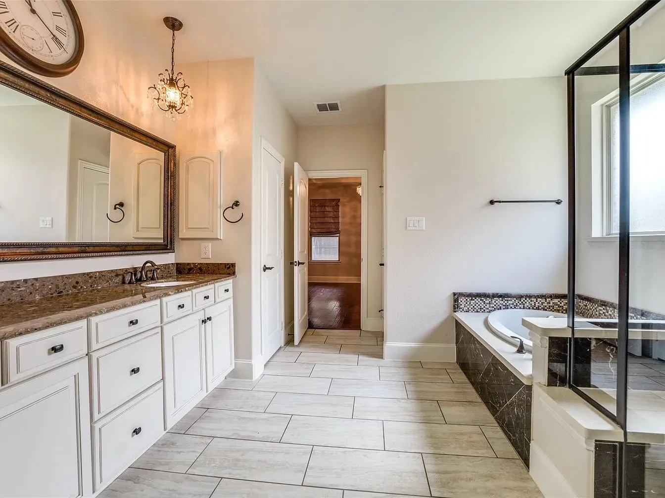 Dual vanity with solid surface countertop, soaking tub with tile surround, walk-in shower with glass enclosure, and tile flooring