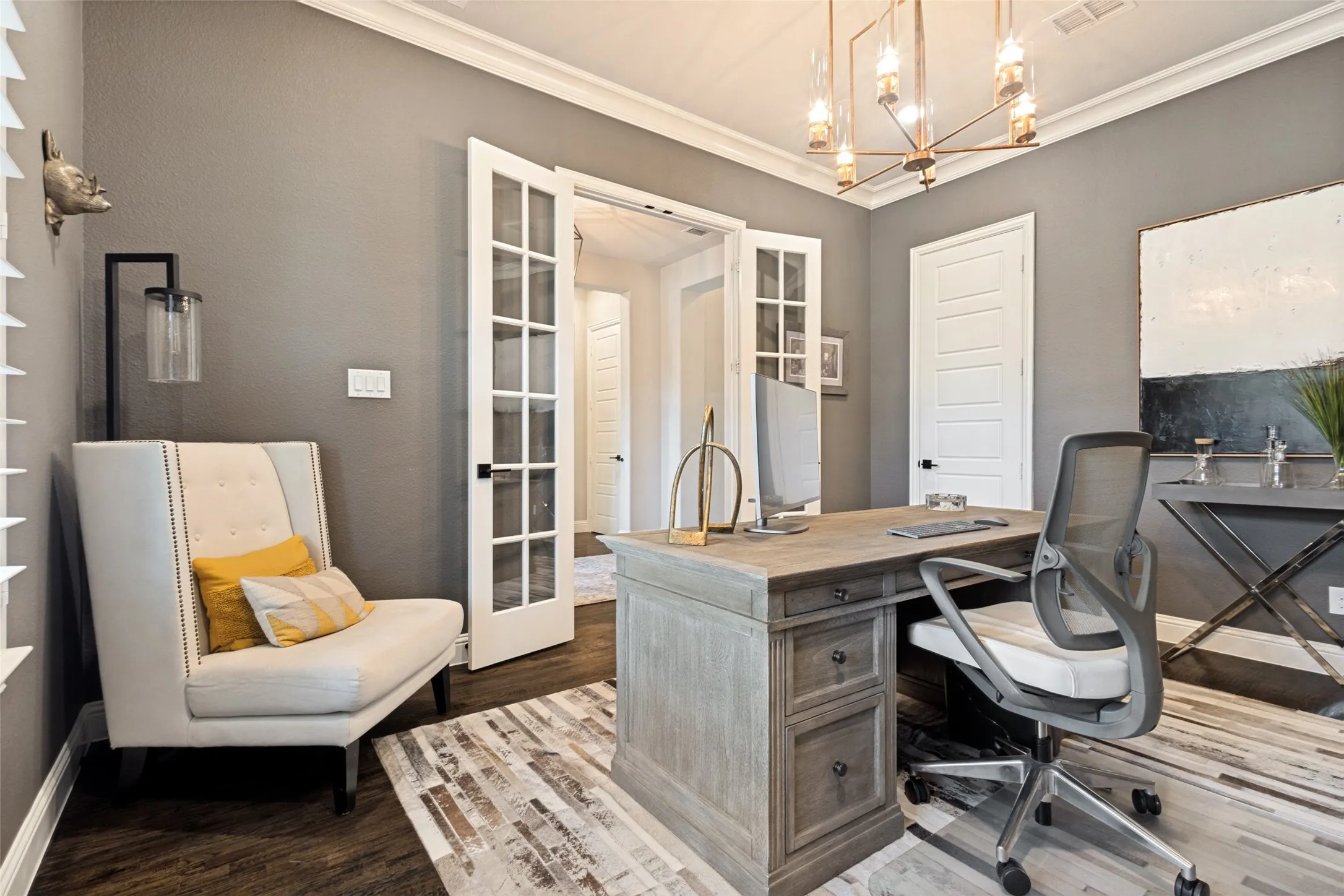 Dedicated office space featuring French doors, dark solid hand-scraped hardwood flooring, crown molding, plantation shutters and a contemporary chandelier