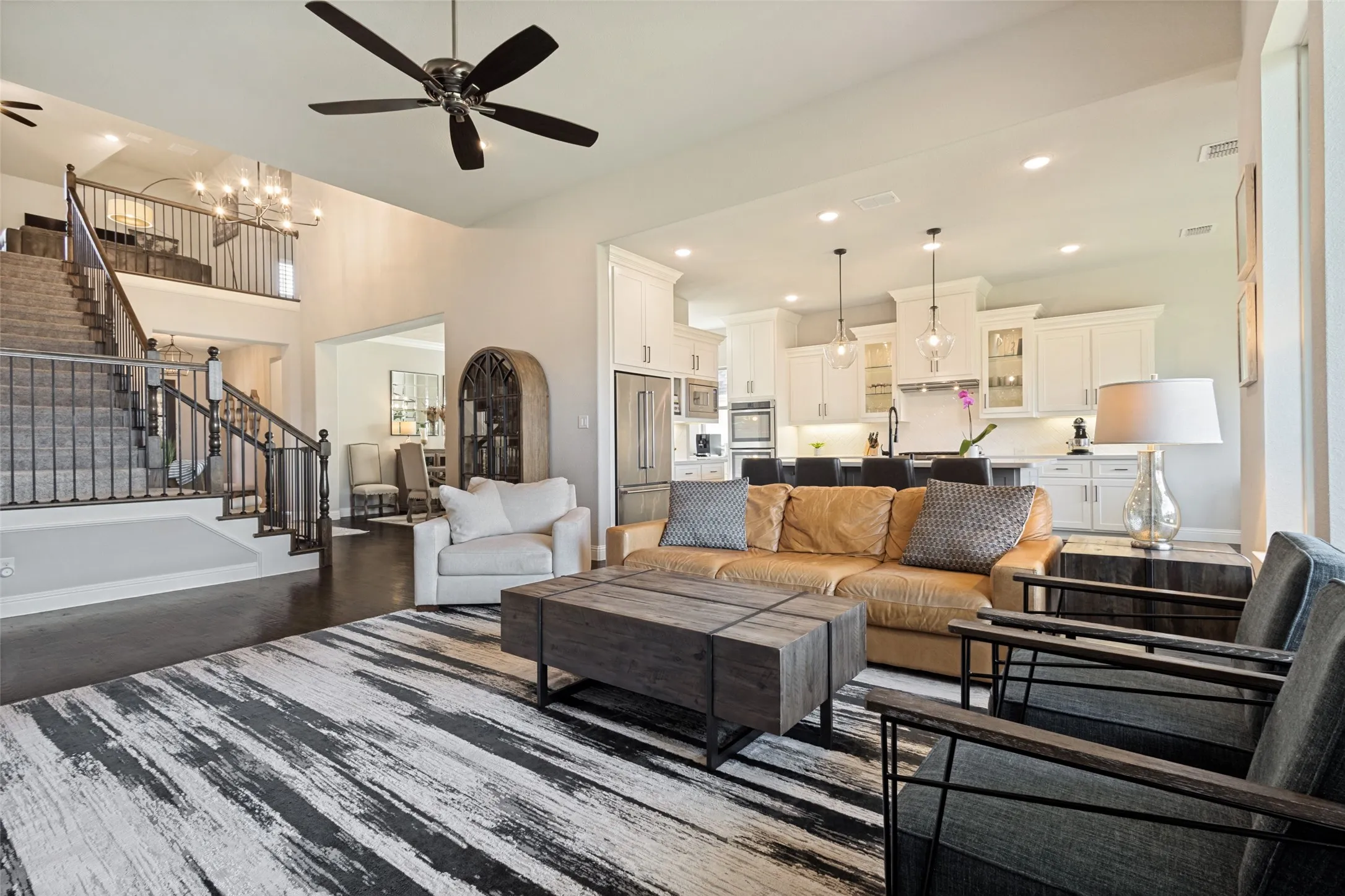 Spacious open-concept living area featuring dark wood-finish flooring, a prominent staircase with dark wood newel posts and wrought iron balusters