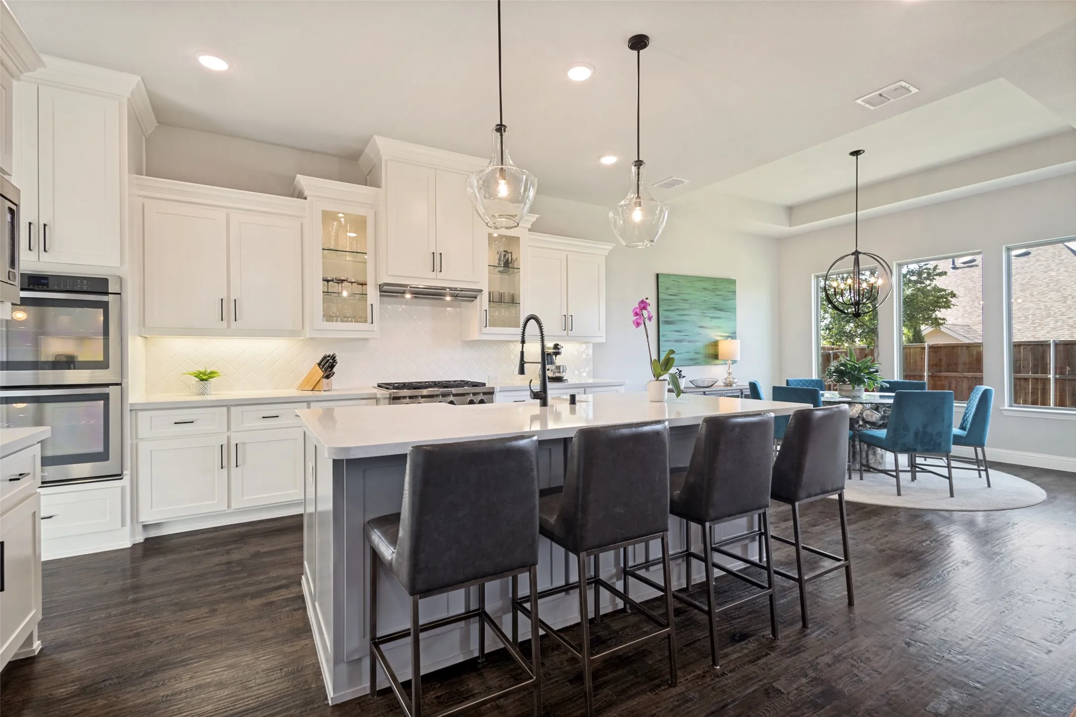 Open-concept kitchen featuring solid custom white shaker cabinetry, stainless steel double ovens, and a large island with seating for 4