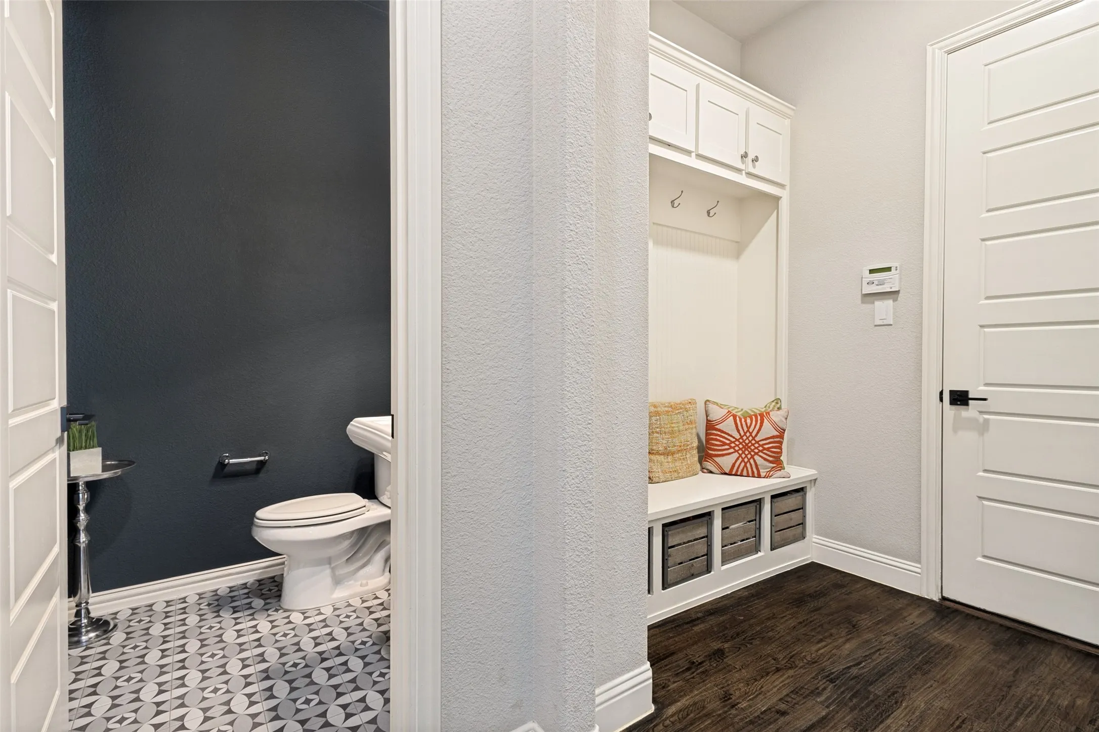 Built-in mudroom bench with upper cabinetry and storage cubbies are located just off the garage & laundry area with the half bath conveniently centrally located near the family room decorated in a matte dark blue wall tone and spanish ensipred tile.