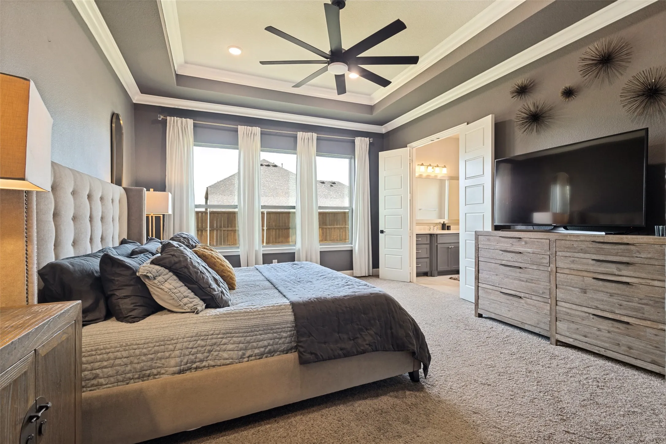 Primary bedroom with tray ceiling with crown molding, ceiling fan, and recessed lighting