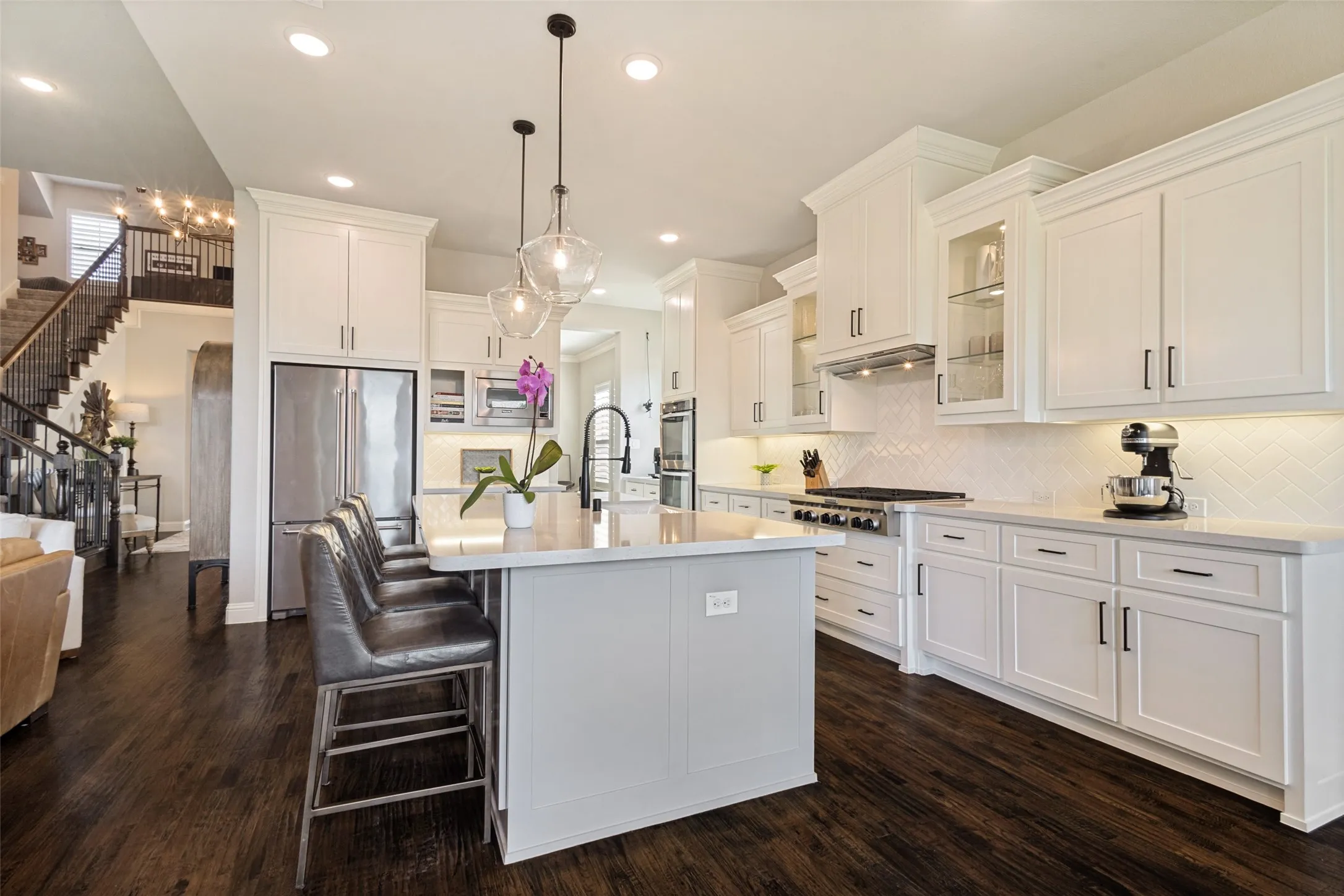 Gourmet kitchen with white cabinetry, stainless steel appliances, and a central island with countertop seating