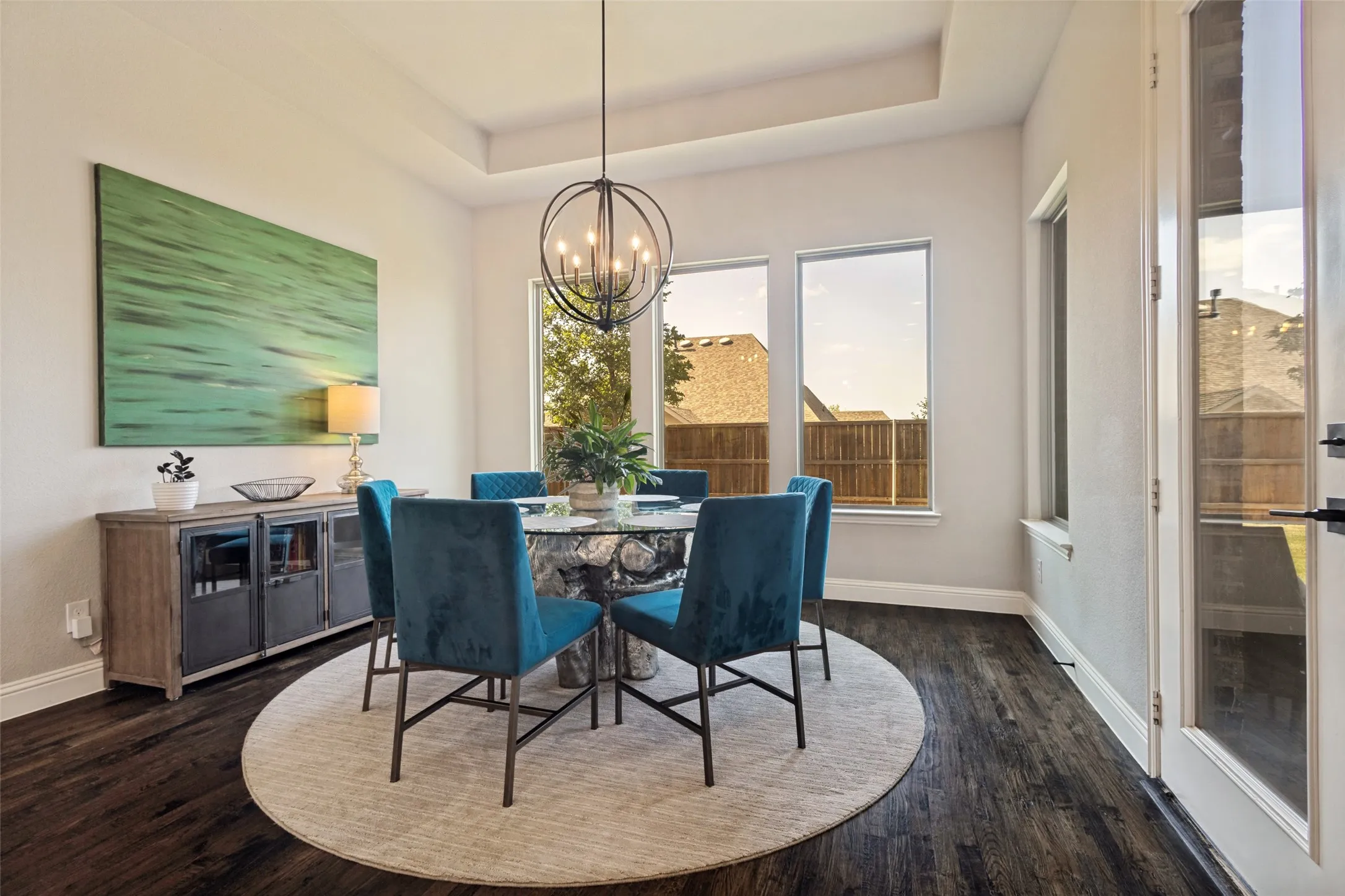 Breakfast area featuring dark solid hardwood flooring, a tray ceiling, a modern spherical chandelier and large picture windows