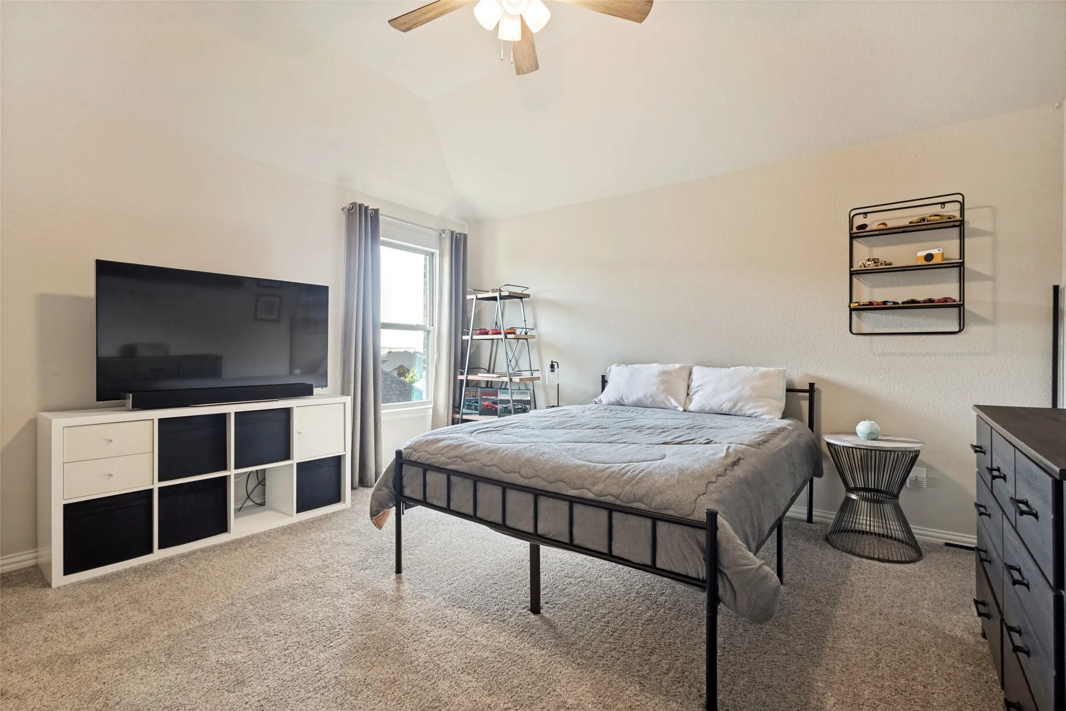 Carpeted bedroom featuring a vaulted ceiling and a ceiling fan