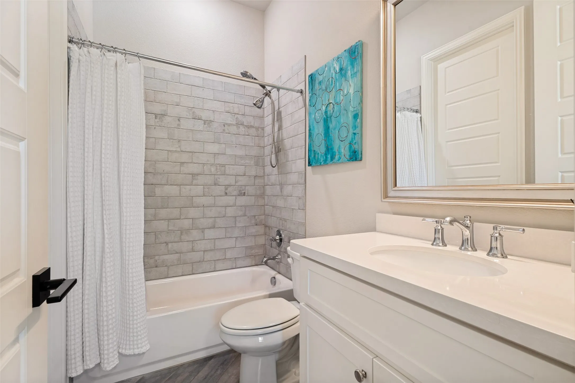 Downstairs bathroom featuring gray tile flooring and shower walls, a white vanity with a light-colored countertop, an undermount sink, chrome fixtures and a walk-in closet