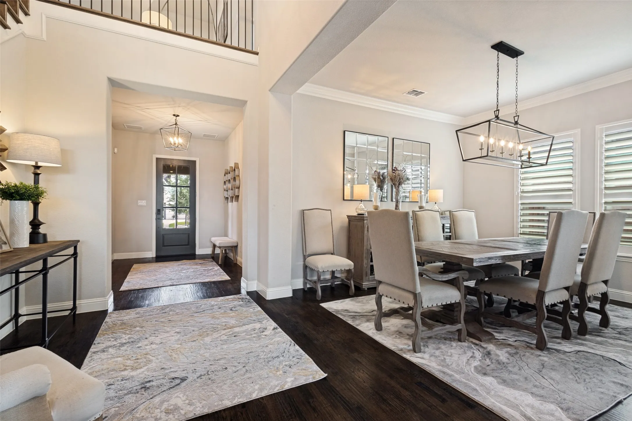 Expansive dining space featuring solid dark hardwood flooring, a contemporary linear chandelier, and plantation shutters
