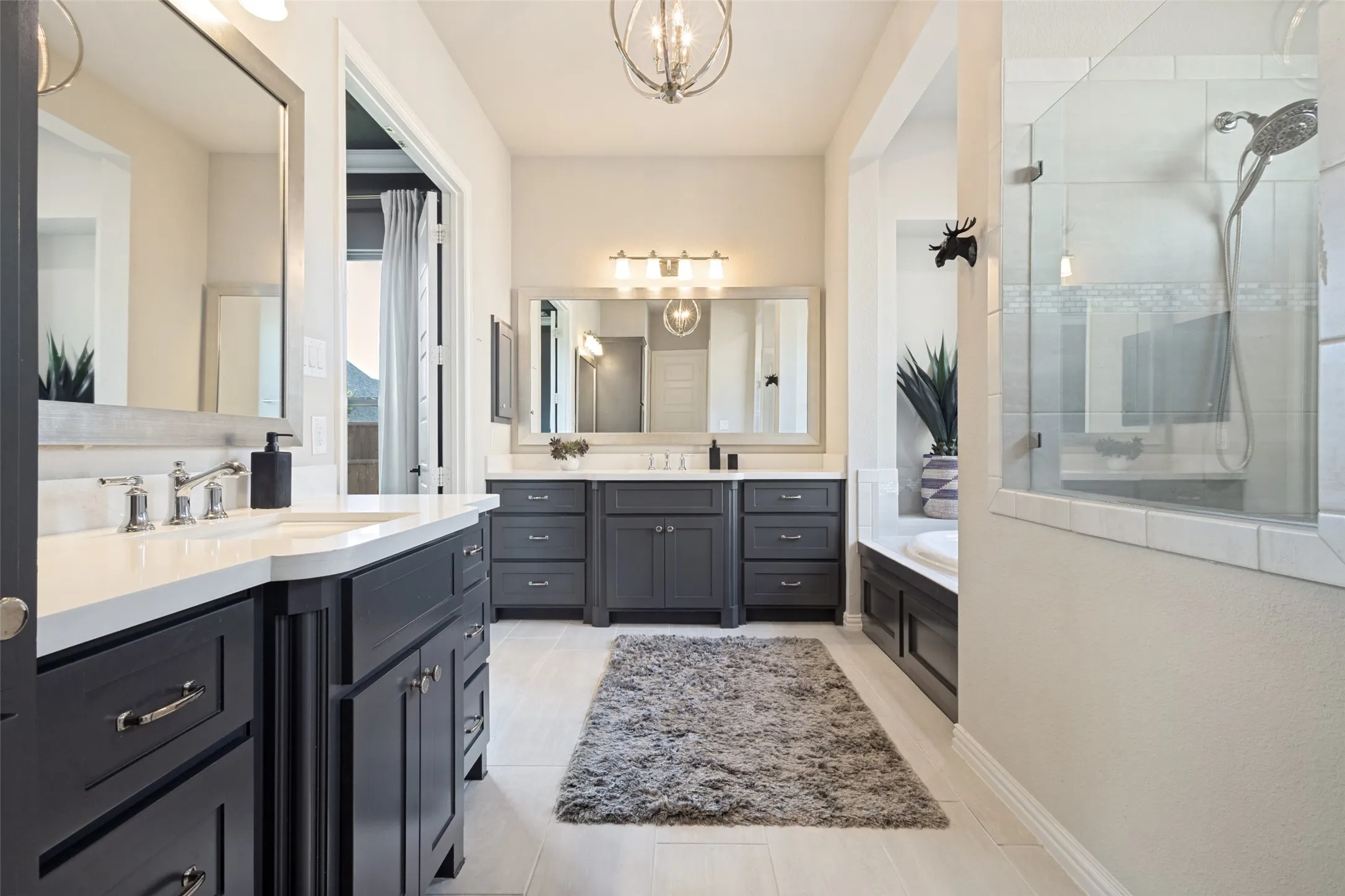 Primary Bathroom with dual vanities, oversized walk-in shower & soaking tub featuring dark cabinetry and white countertops. Don't miss the huge primary closet!