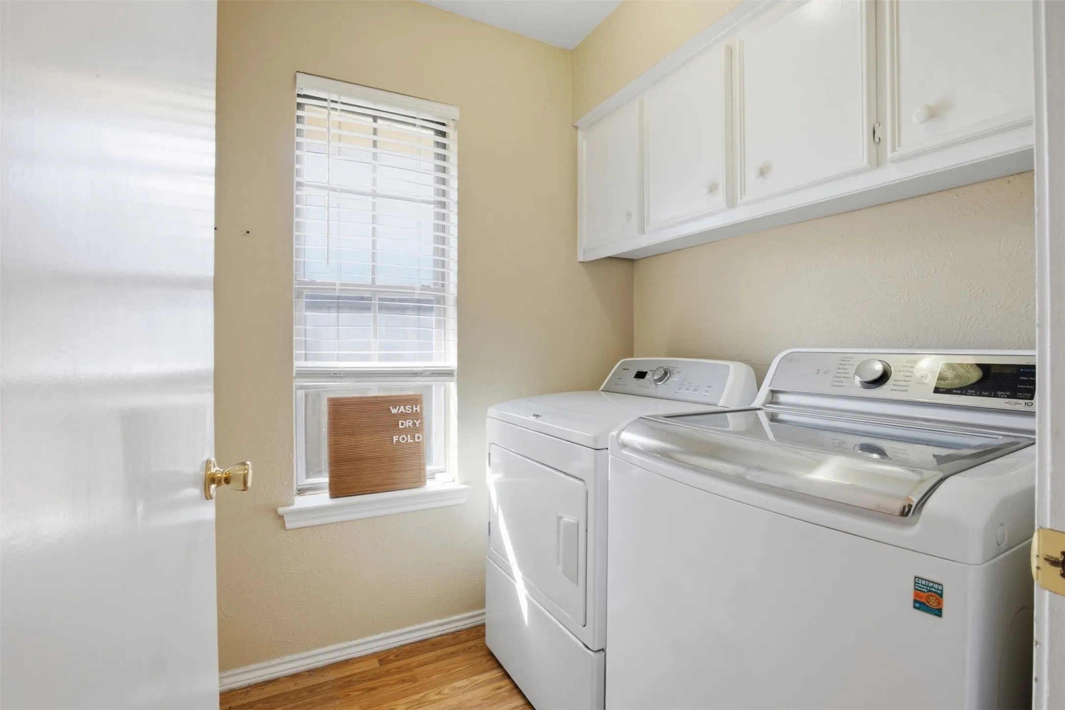 A dedicated laundry room with overhead cabinetry to help keep everyday essentials organized.
