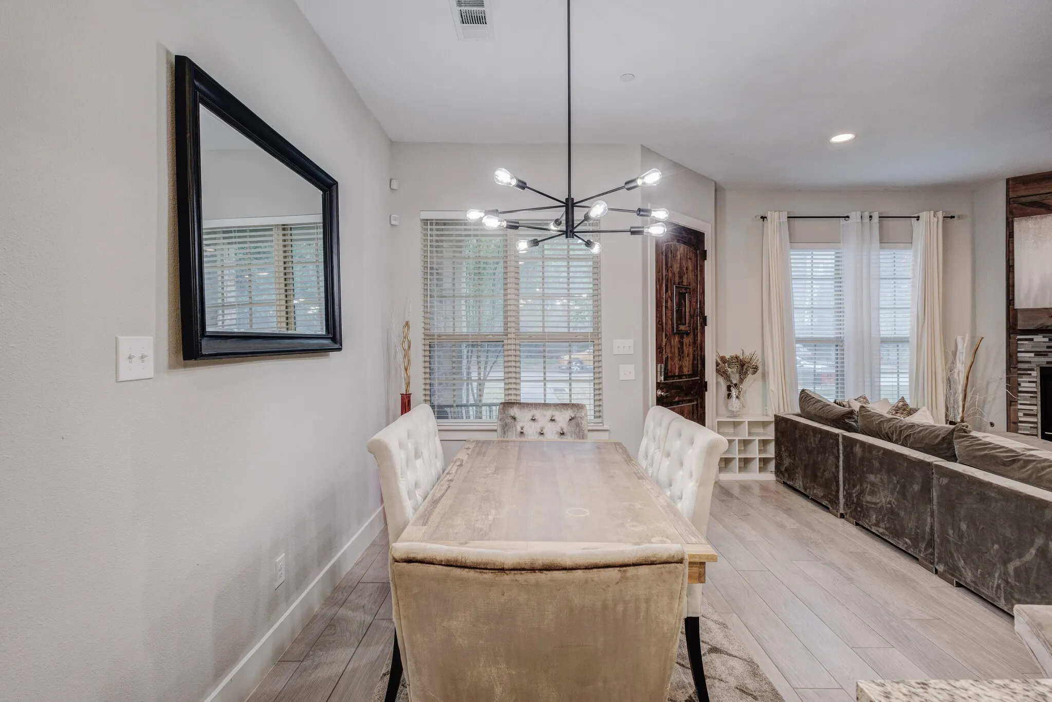 Open-concept dining area featuring wood-finish flooring, a contemporary chandelier, recessed lighting, and ample natural light from multiple windows