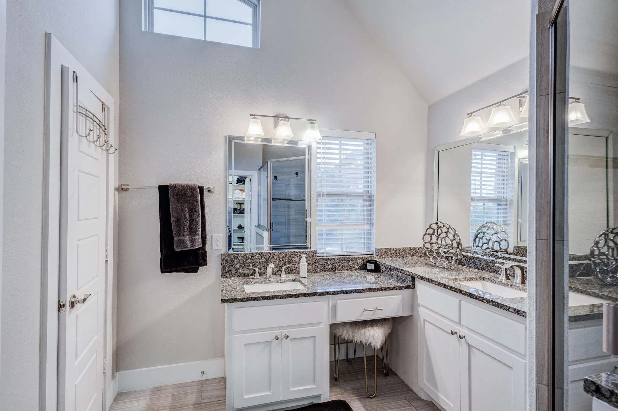 Dual vanity with integrated sinks, granite countertops, and white cabinetry