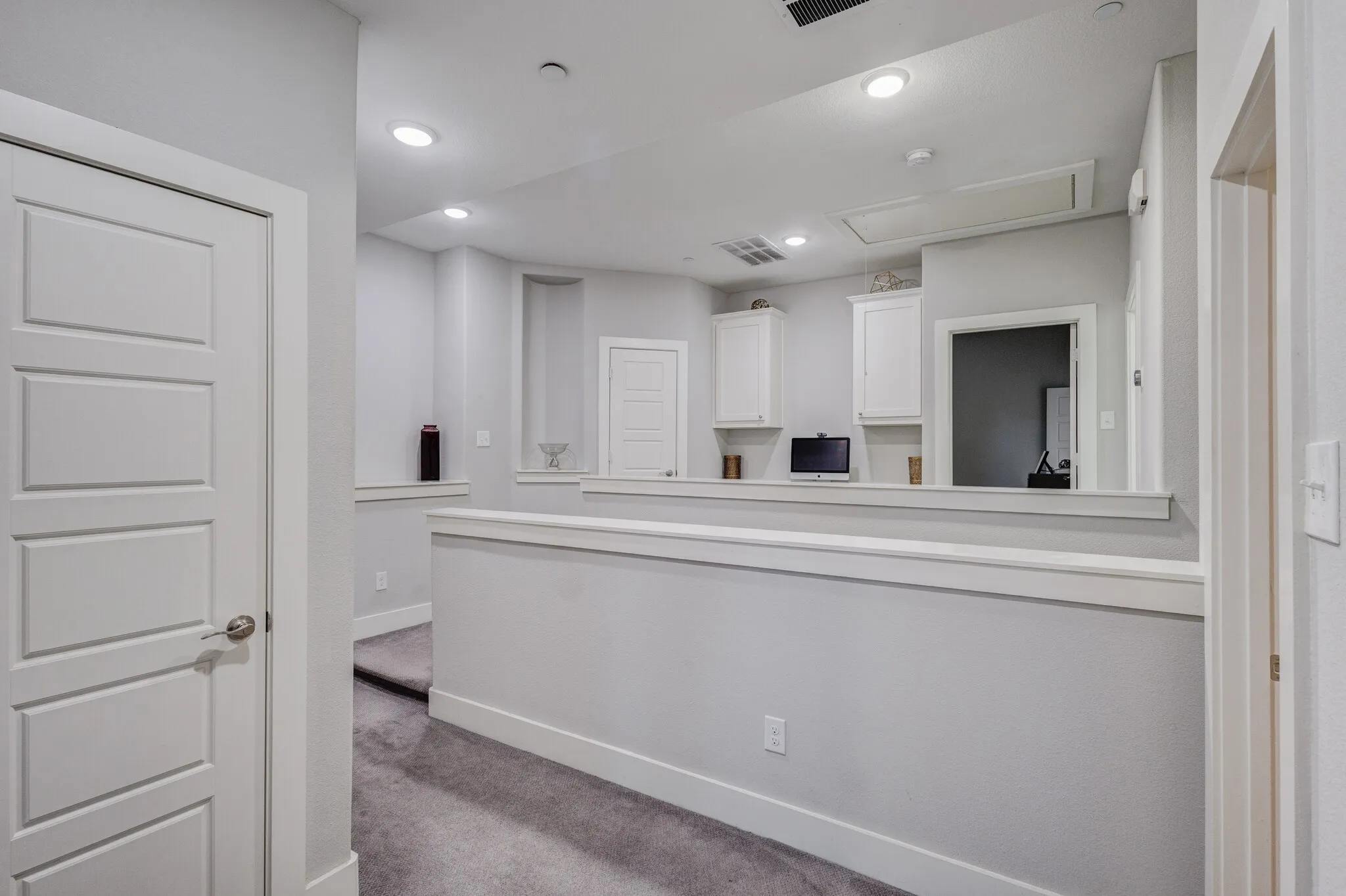Upper-level landing featuring recessed lighting, carpeted flooring, built-in cabinetry, and a half wall with a decorative ledge