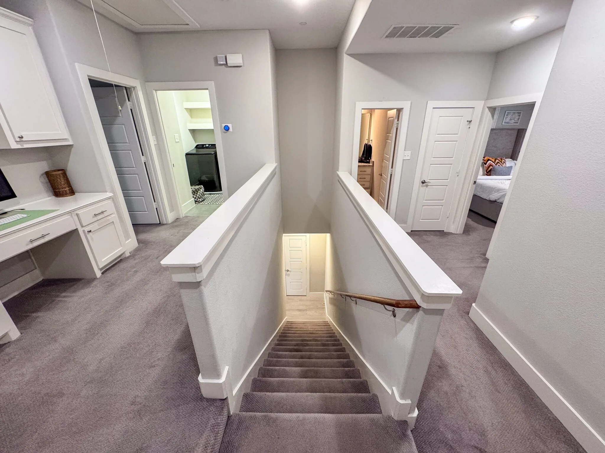 Carpeted staircase and hallway with a built-in desk, paneled doors, and ceiling-mounted lighting