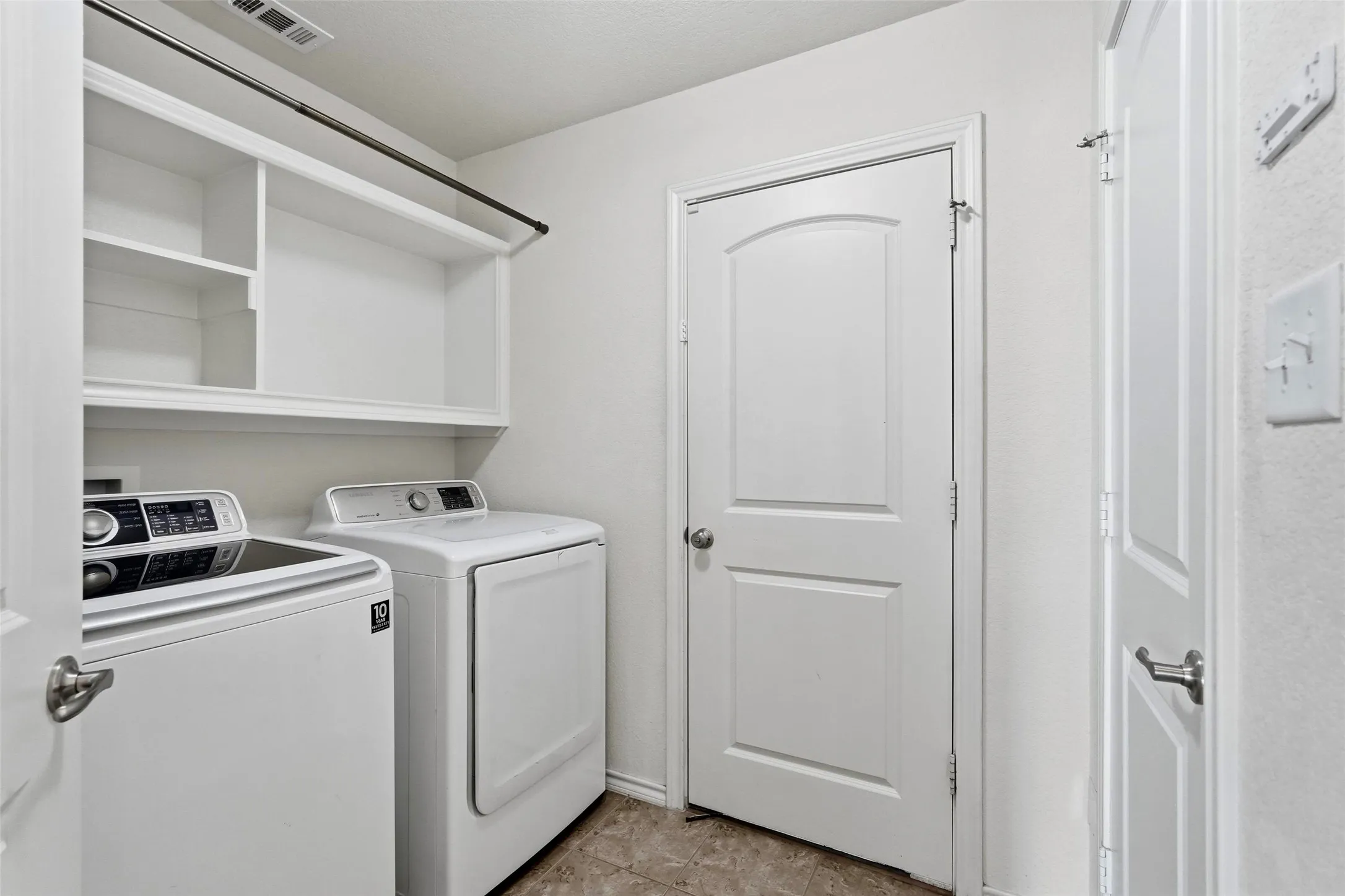 Laundry area featuring built-in shelving, a hanging rod, and tile flooring