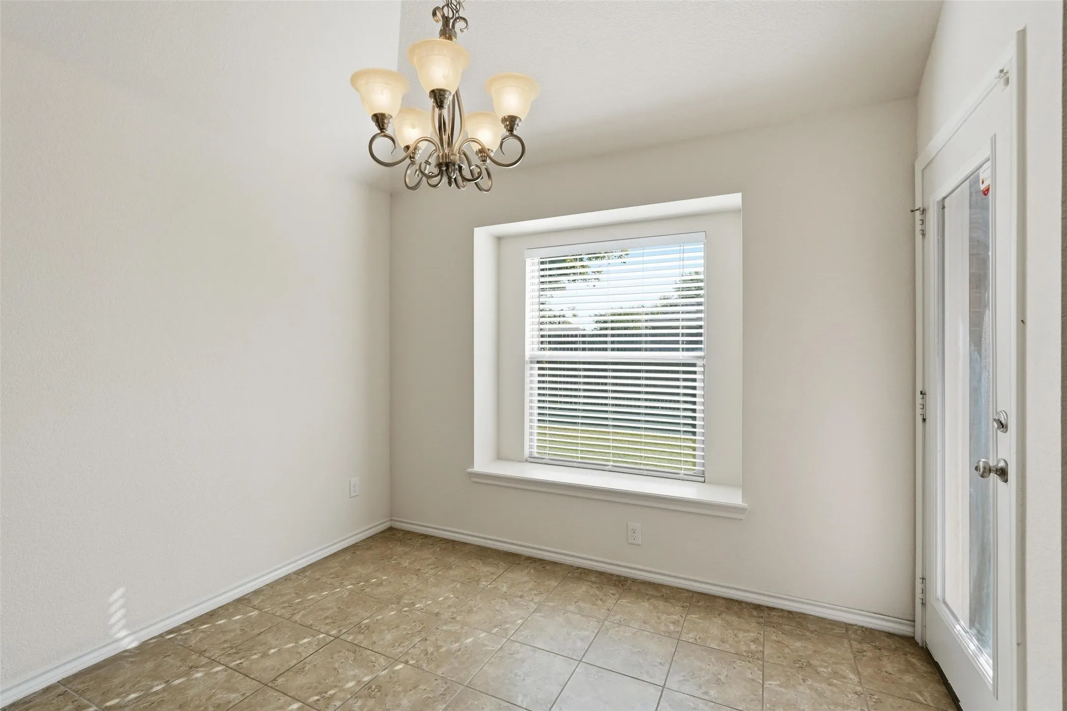 Recessed window with blinds, tile flooring, a glass-paned door, and an ornate five-light chandelier