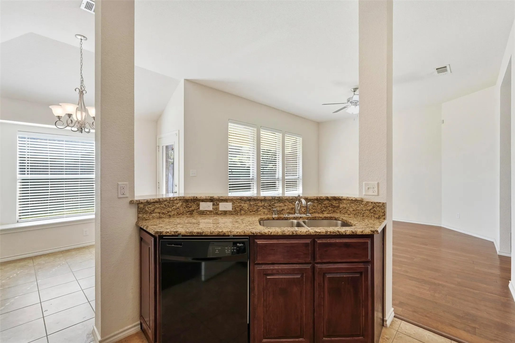 Kitchen pass-through with dual basin sink, integrated dishwasher, and granite countertops