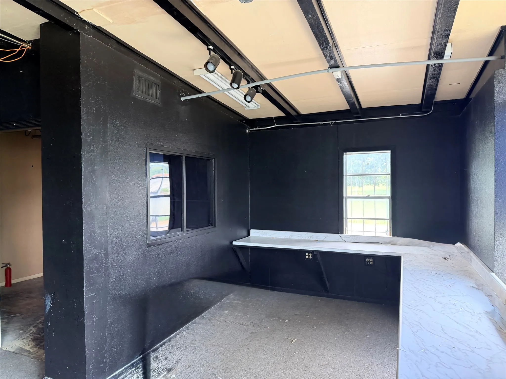Exposed ceiling beams, track lighting, built-in shelving, two windows