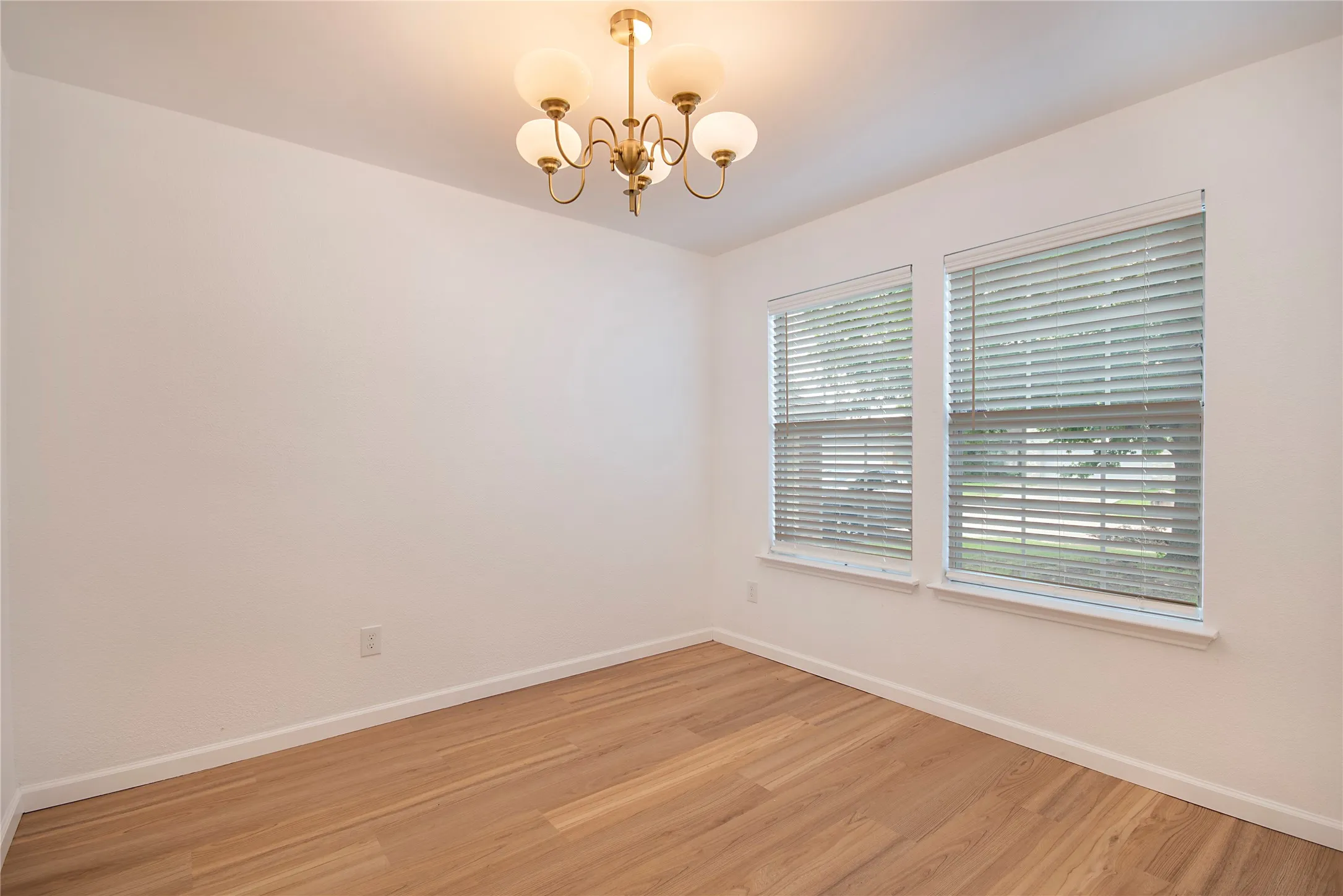 Recessed lighting fixture, wood-finish flooring, two large windows with blinds, and white wall finishes