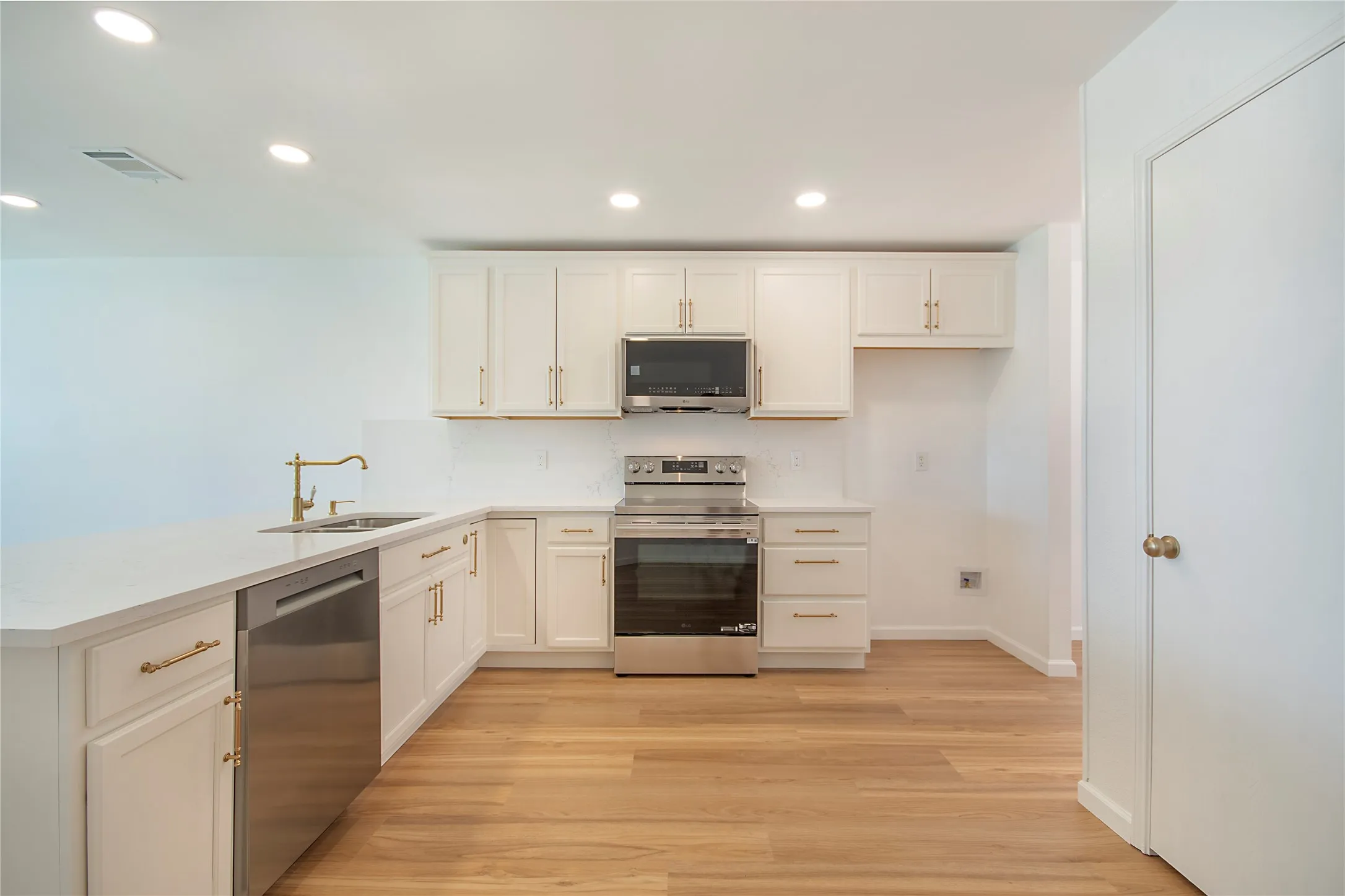 Kitchen featuring white cabinetry, stainless steel appliances, wood-finish flooring, and recessed lighting