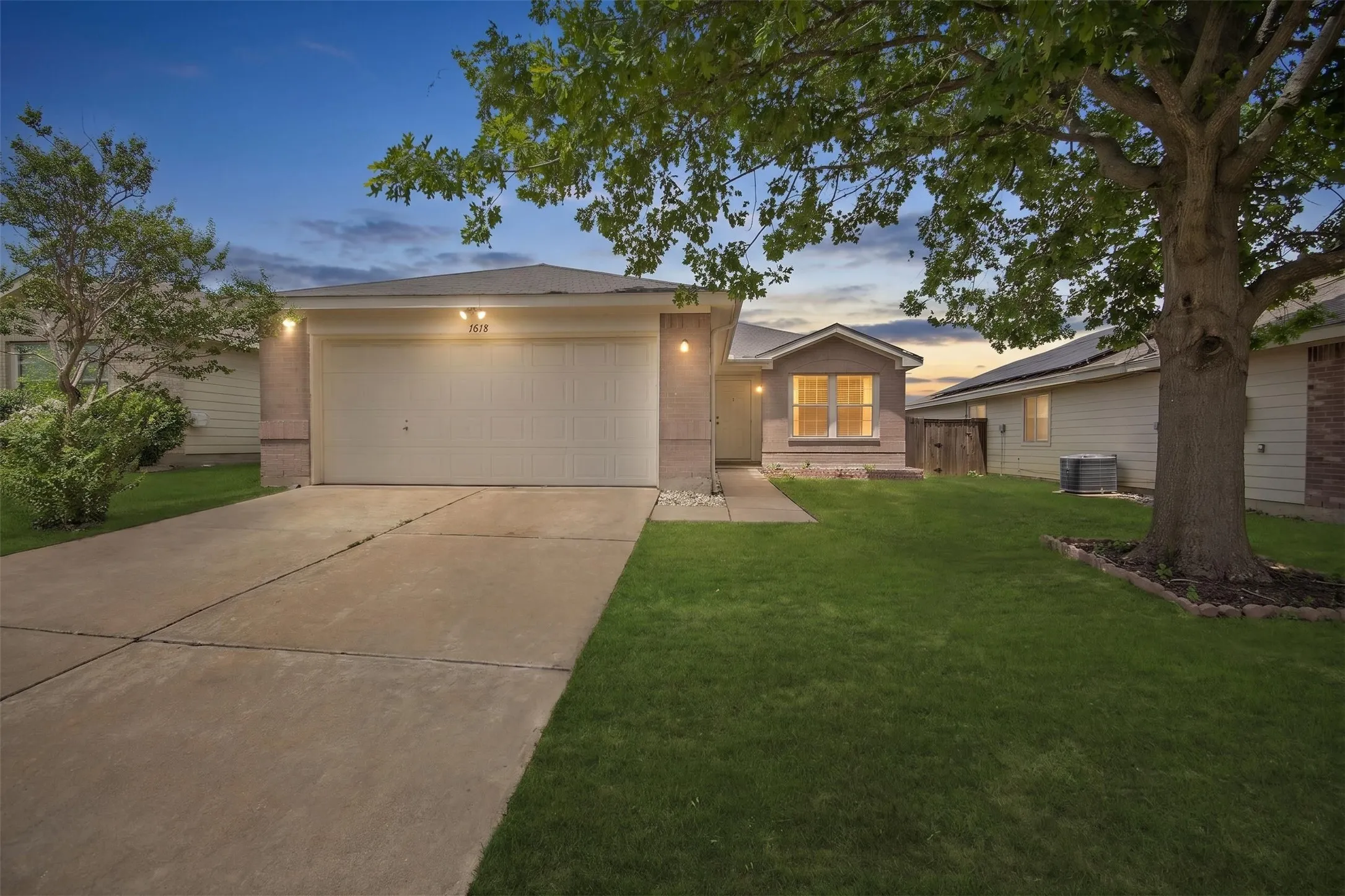 Exterior featuring a two-car garage, concrete driveway, and a mature tree