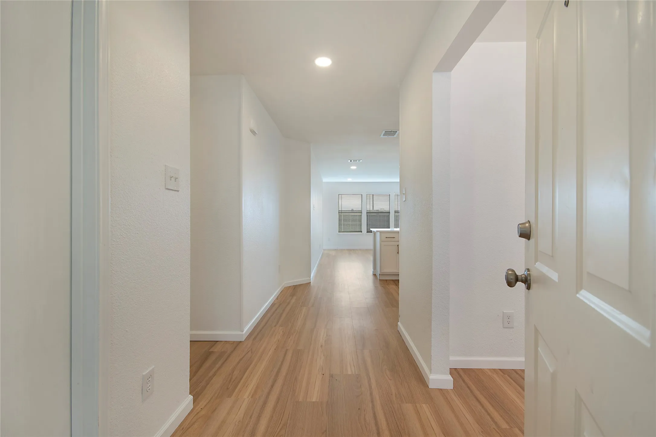 Entryway featuring wood-finish flooring, recessed lighting, and a paneled door with brushed nickel hardware
