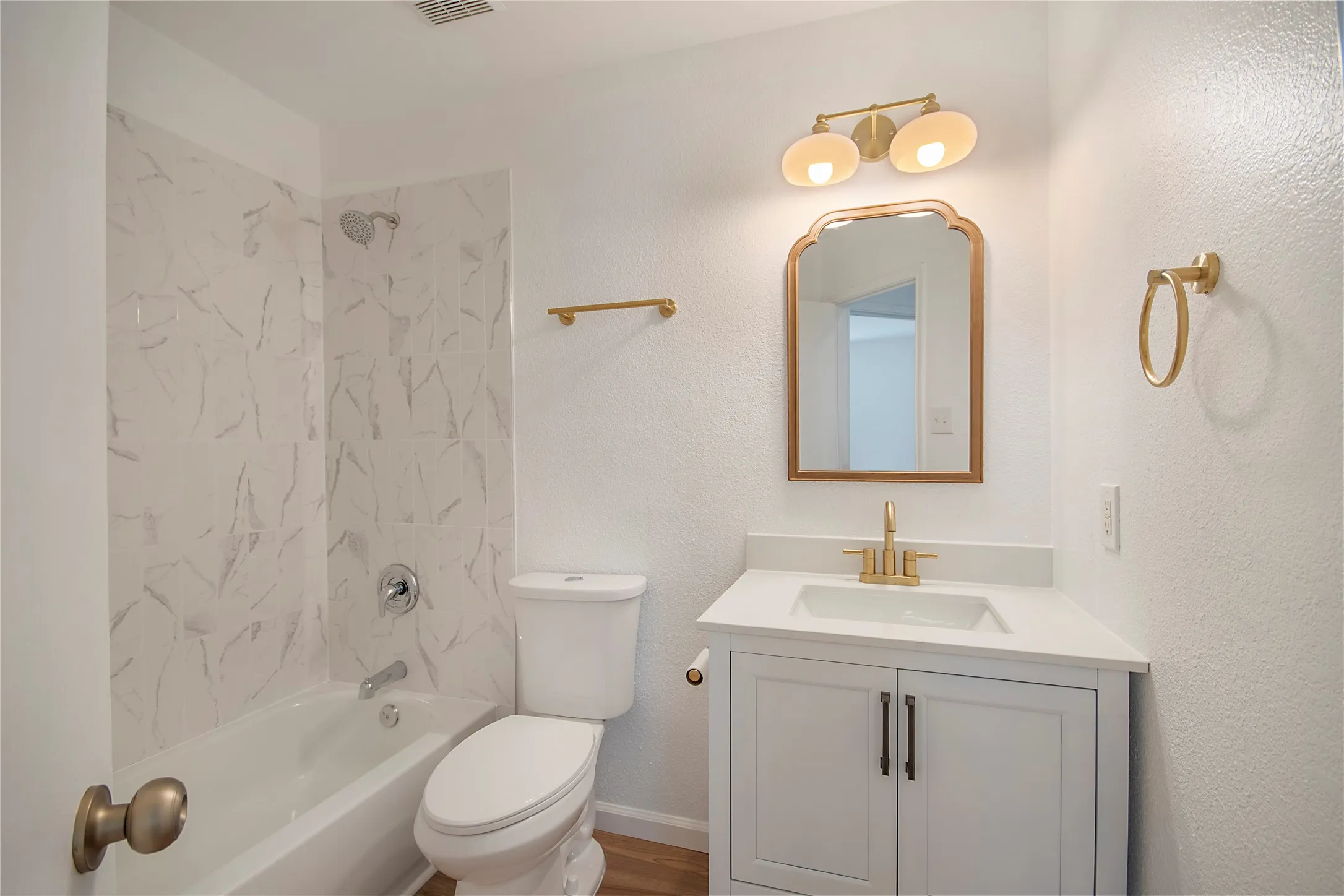 White vanity with a white countertop and rectangular sink, gold-finish faucet, and a gold-framed​​‌​​​​‌​​‌‌​‌‌​​​‌‌​‌​‌​‌​​​‌​​ mirror