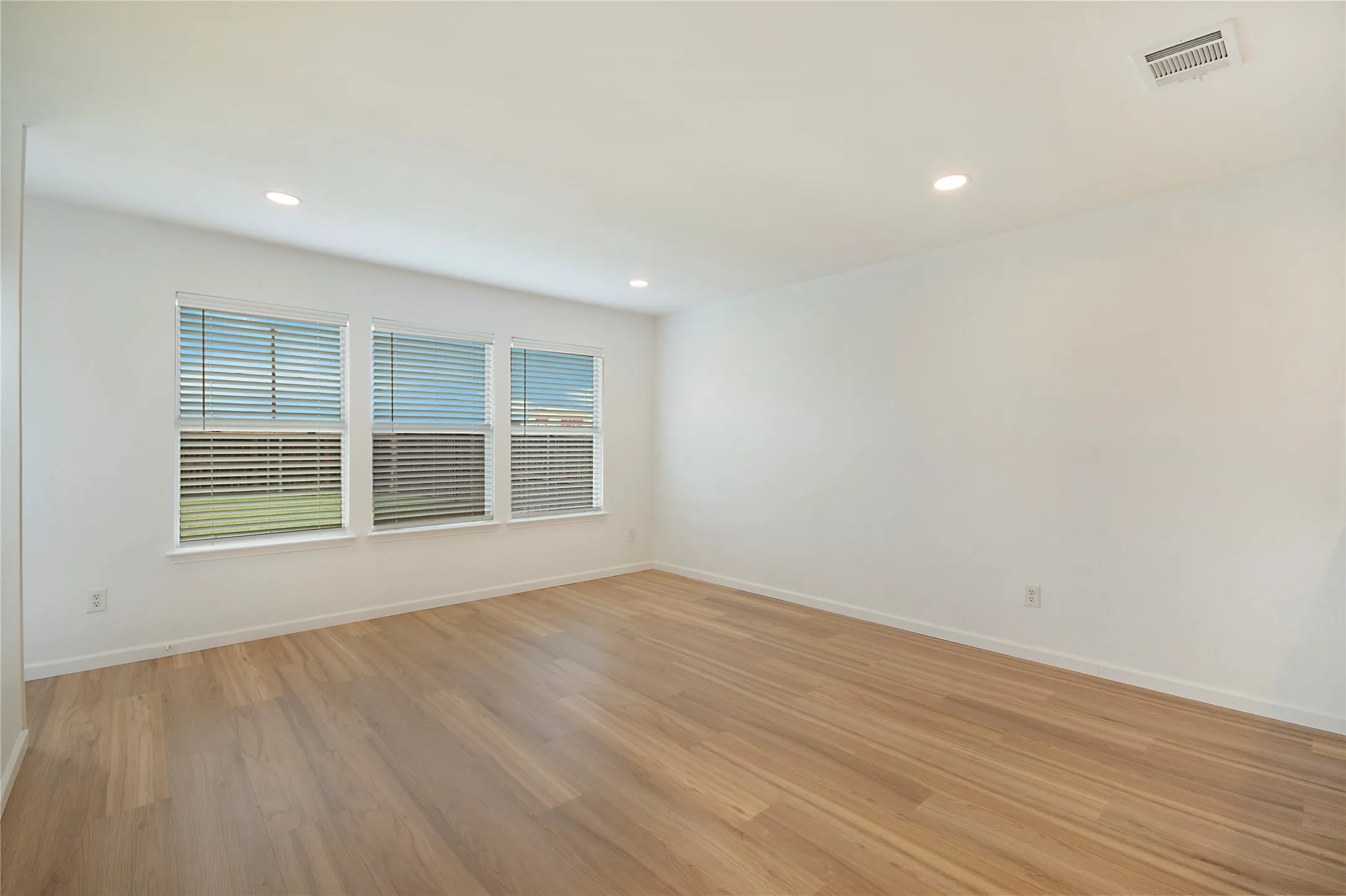 Recessed lighting, wood-finish flooring, white walls, multiple windows, and white window blinds