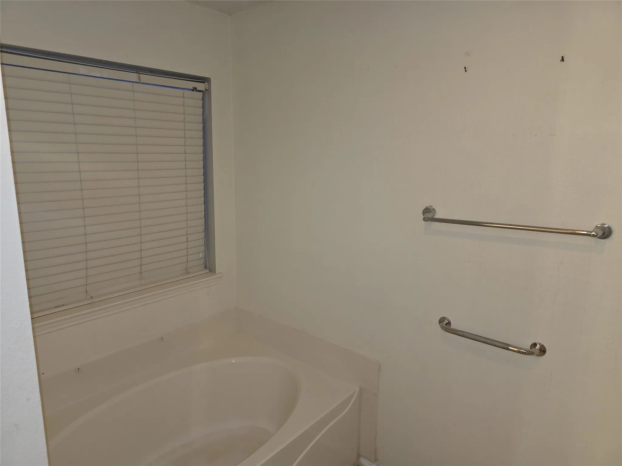 Built-in soaking tub with a window and horizontal blinds