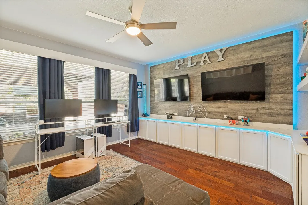 Versatile downstairs media or game room with built-in cabinetry and a stylish statement wall—perfect for movie nights or play.