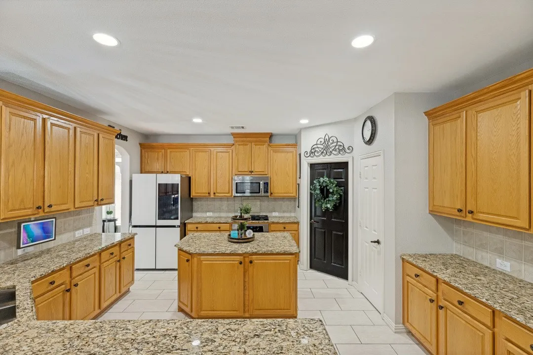 Beautifully designed kitchen with abundant cabinetry, granite countertops, and a spacious walk-in pantry offering exceptional storage and organization.