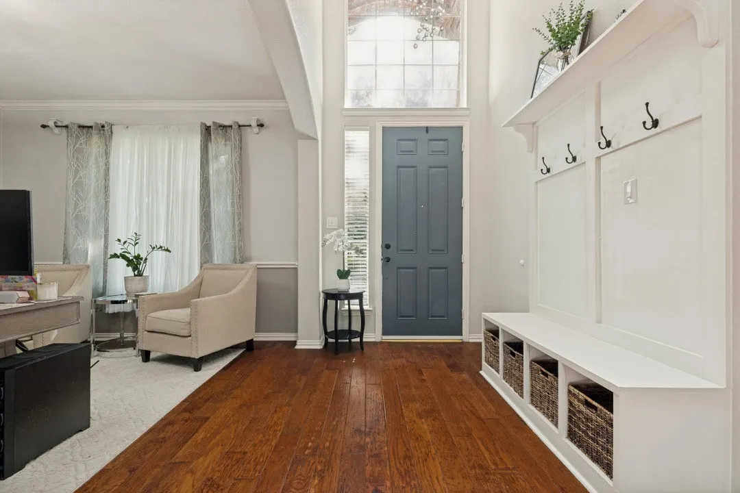 Bright, welcoming foyer featuring abundant natural light, a decorative chandelier, and a custom built-in drop zone for everyday convenience.