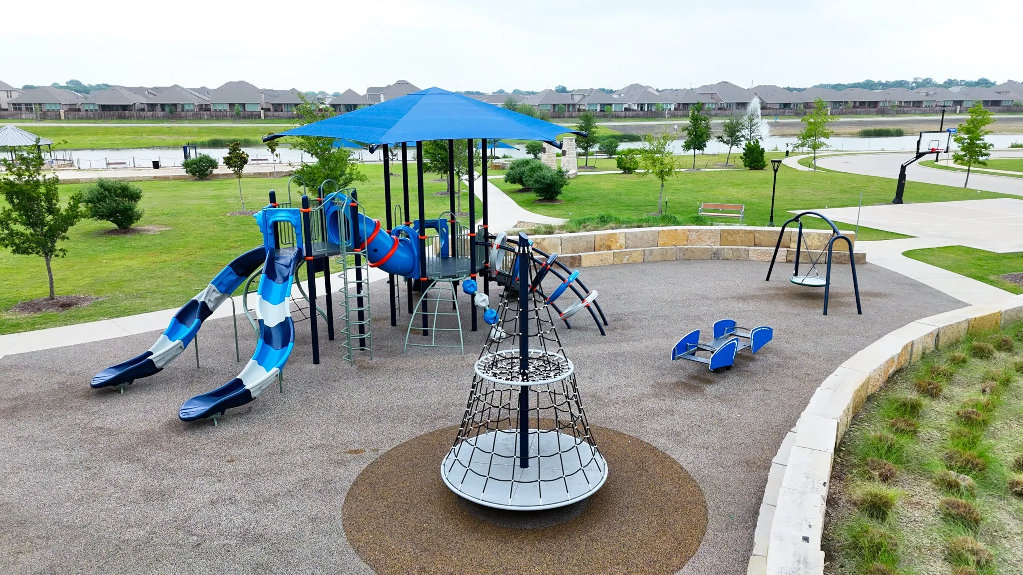 Expansive playground featuring multiple slides, climbing structures, swings, and a resilient rubberized surface