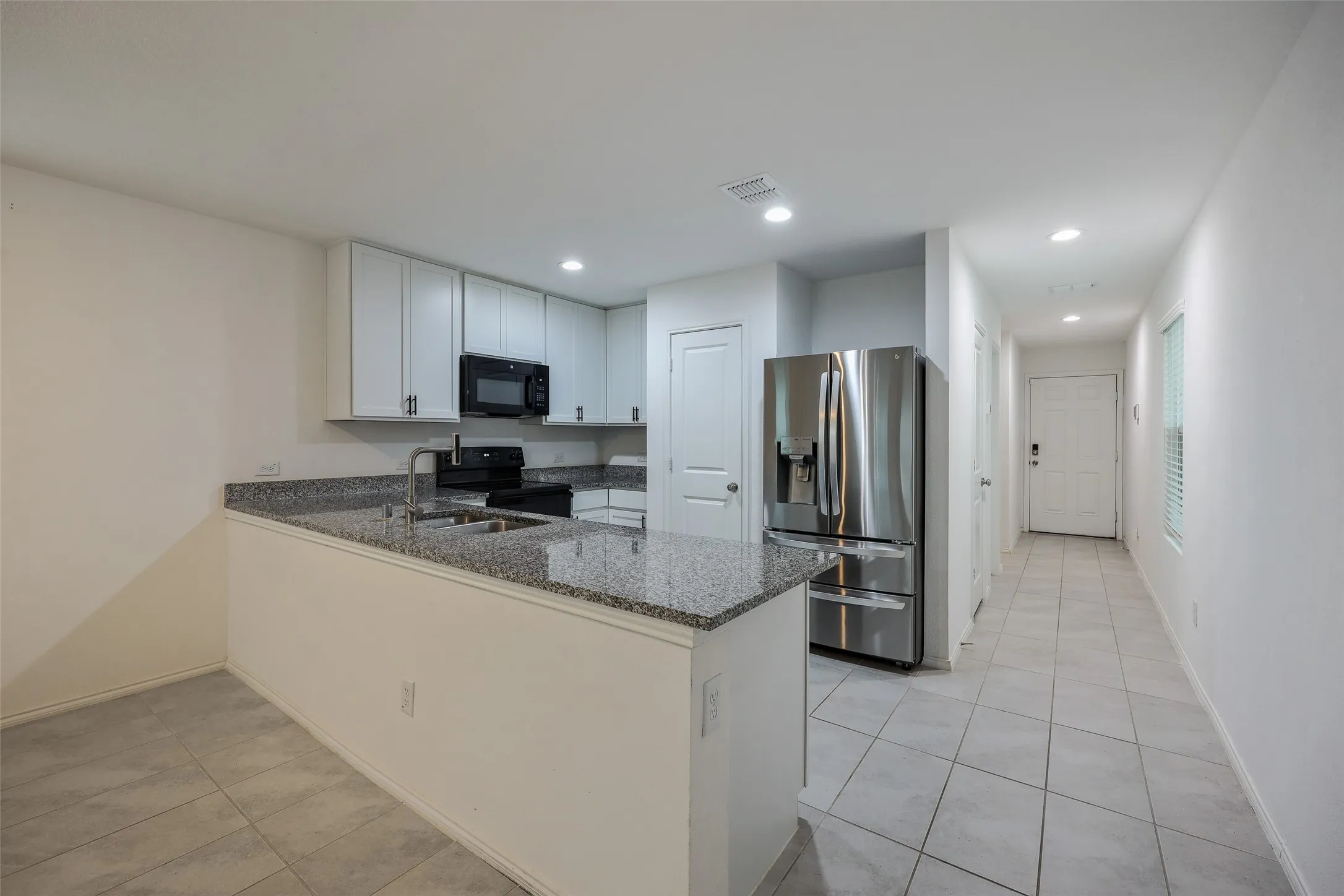 Kitchen featuring an integrated breakfast bar, light cabinetry, and granite countertops