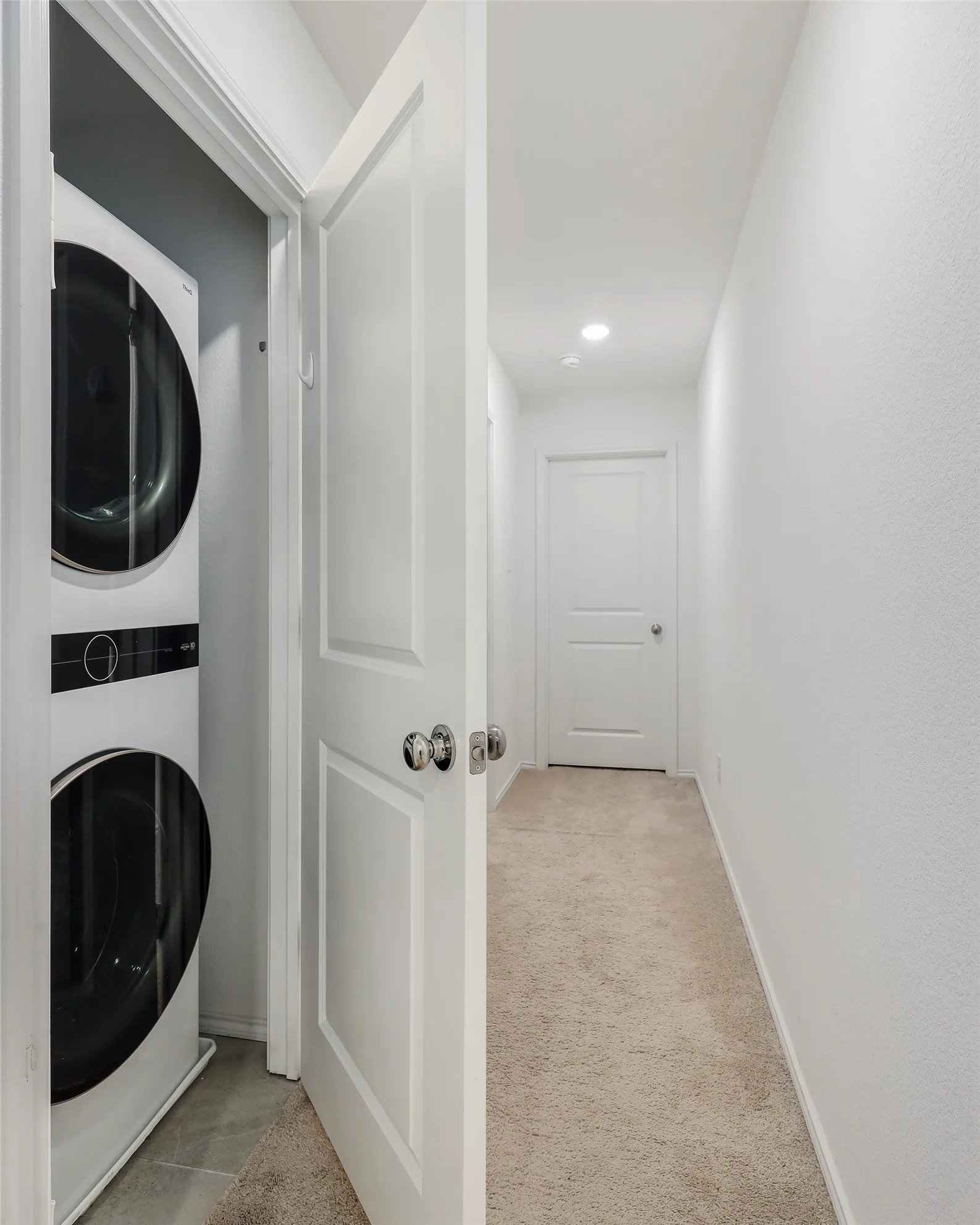 Integrated laundry closet with stacked appliances and tiled flooring