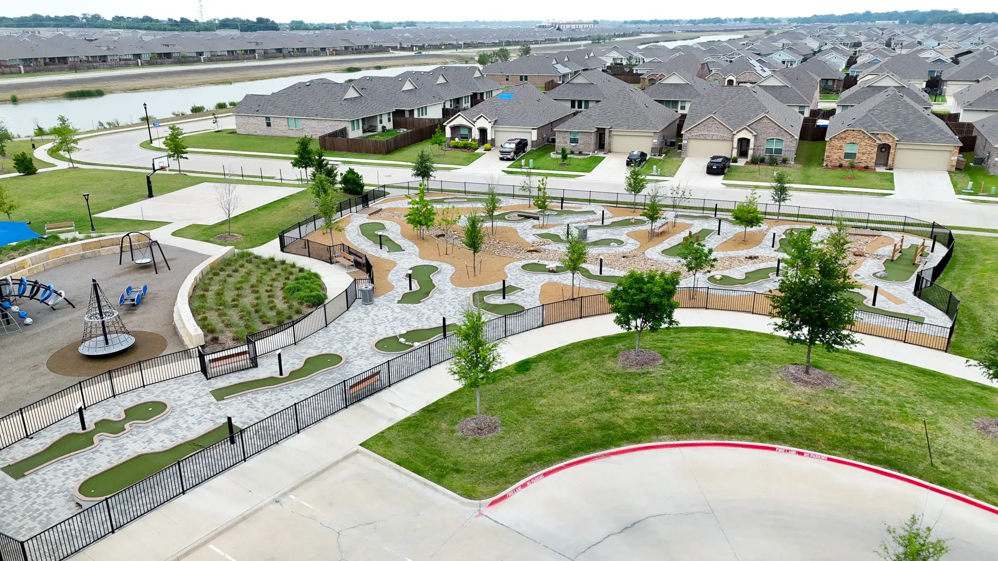 Community amenities featuring a putting green, playground structures, paved walkways, and established trees